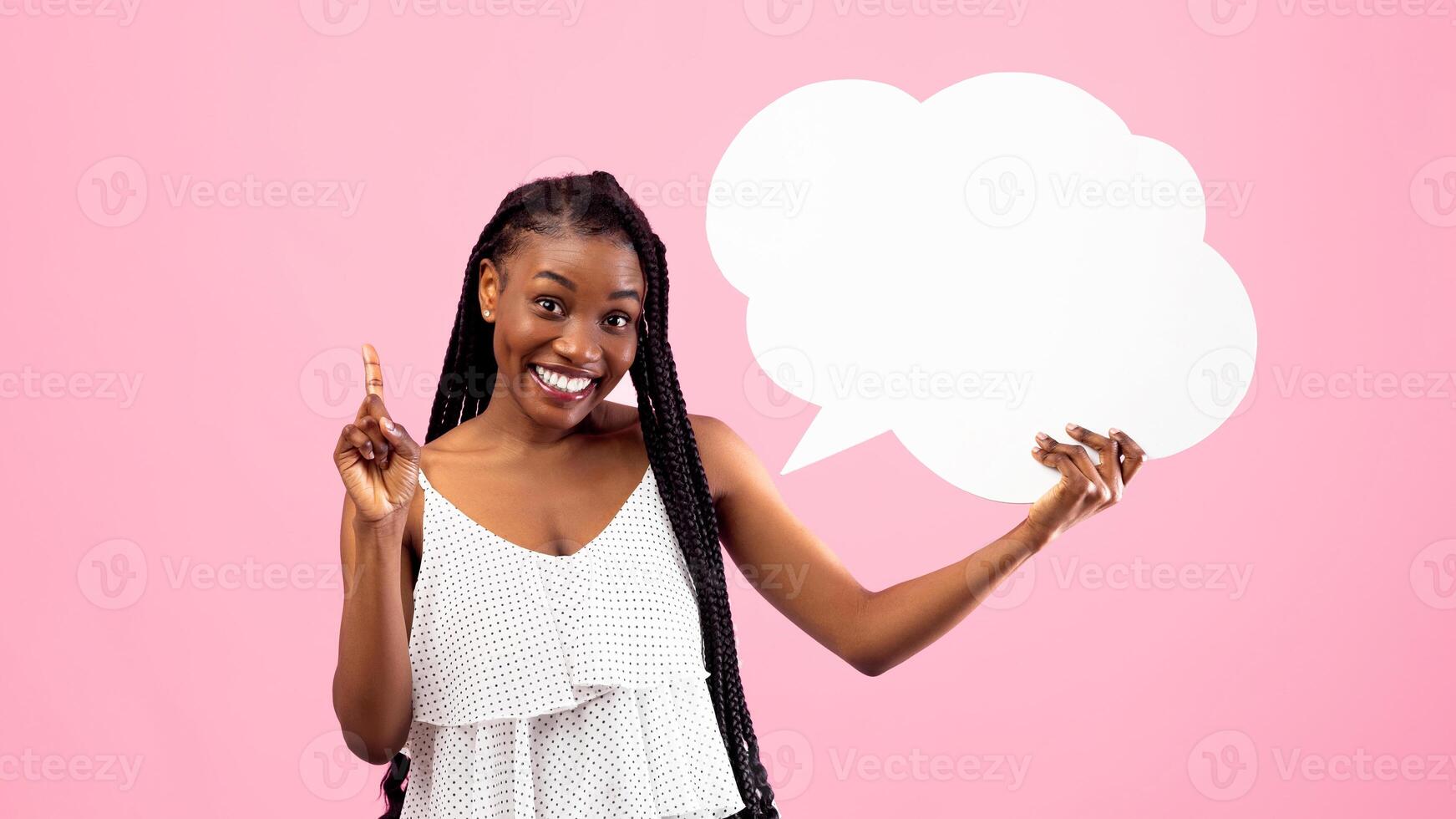 Positive black woman with afro bunches holding blank speech bubble, making IDEA gesture on pink studio background, mockup. Lovely African American lady with empty word cloud, free space photo