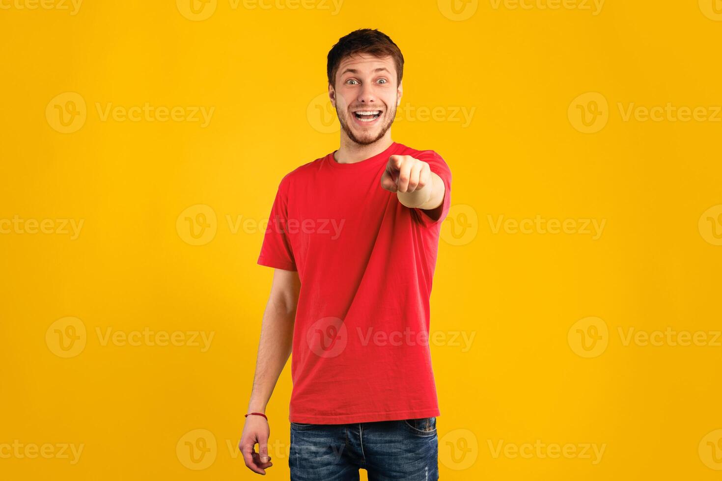 Gotcha, It's You. Portrait of excited surprised bearded man pointing finger at camera, standing isolated over blue studio background, copy space. Shocked guy in yellow shirt laughing and mocking photo