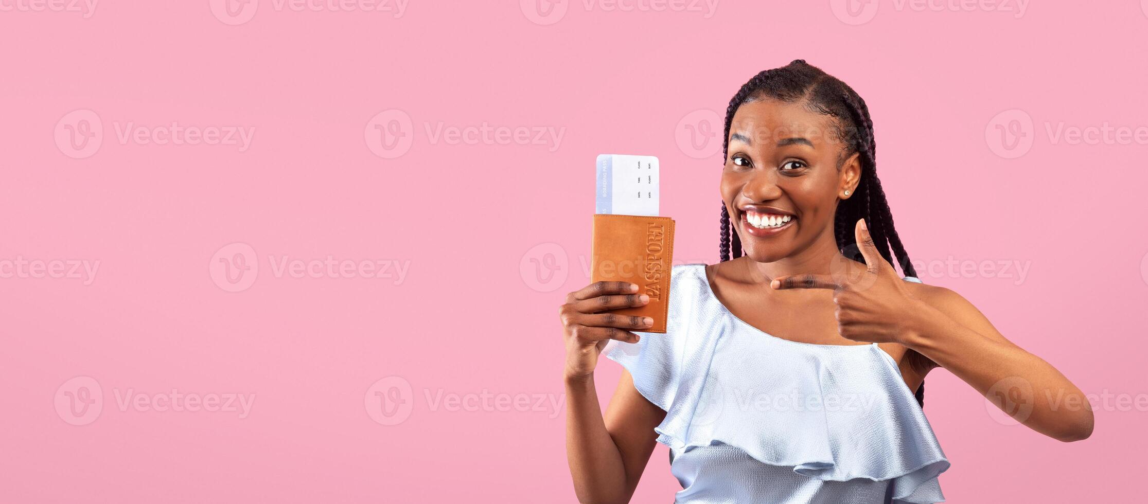Excited young black woman pointing at passport and plane tickets, going on abroad vacation, traveling overseas over pink studio background. Tourism, summer holidays concept photo