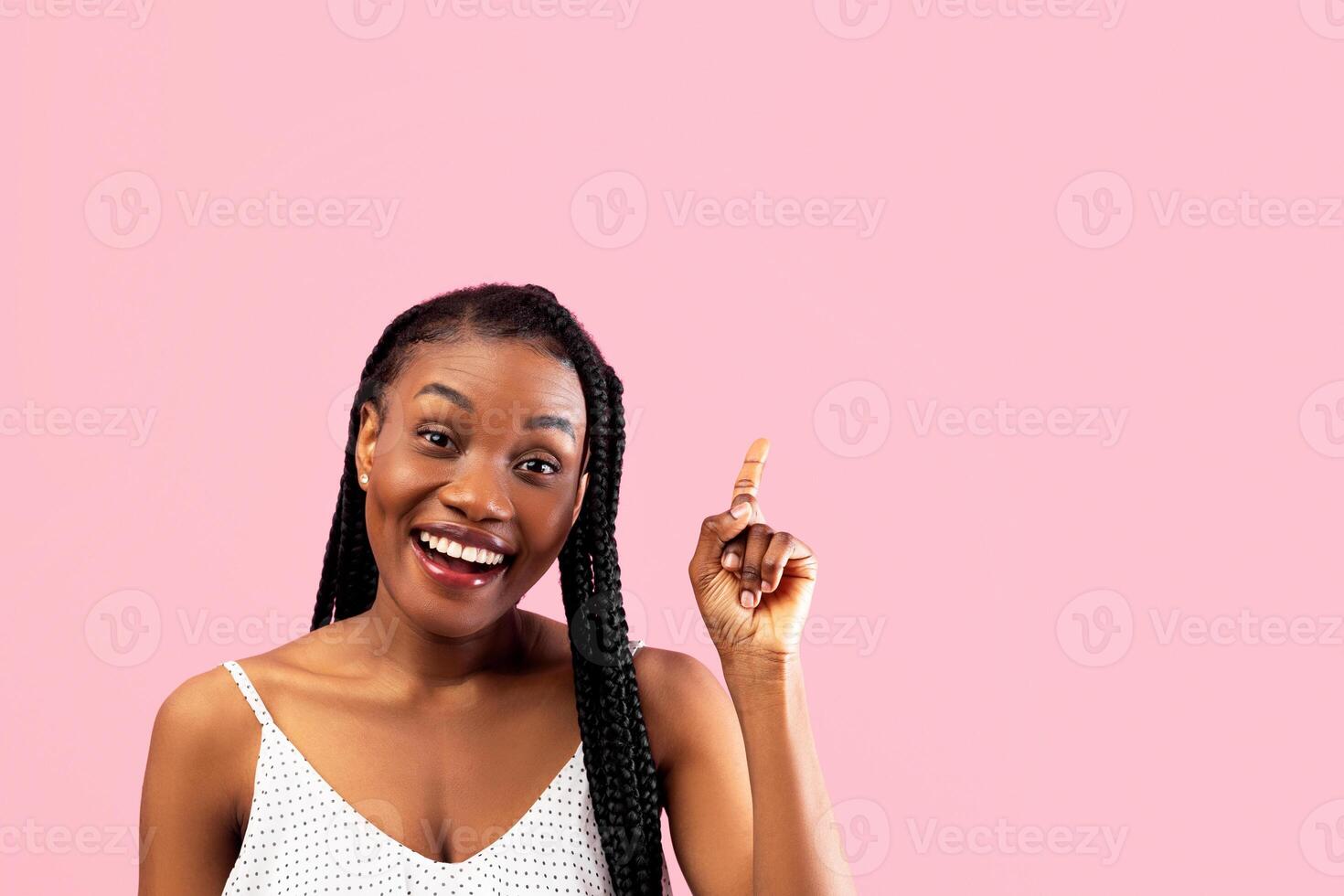 Young black lady in summer clothes pointing upwards on pink studio background. Millennial African American woman experiencing AHA moment, having creative idea, gesturing eureka photo