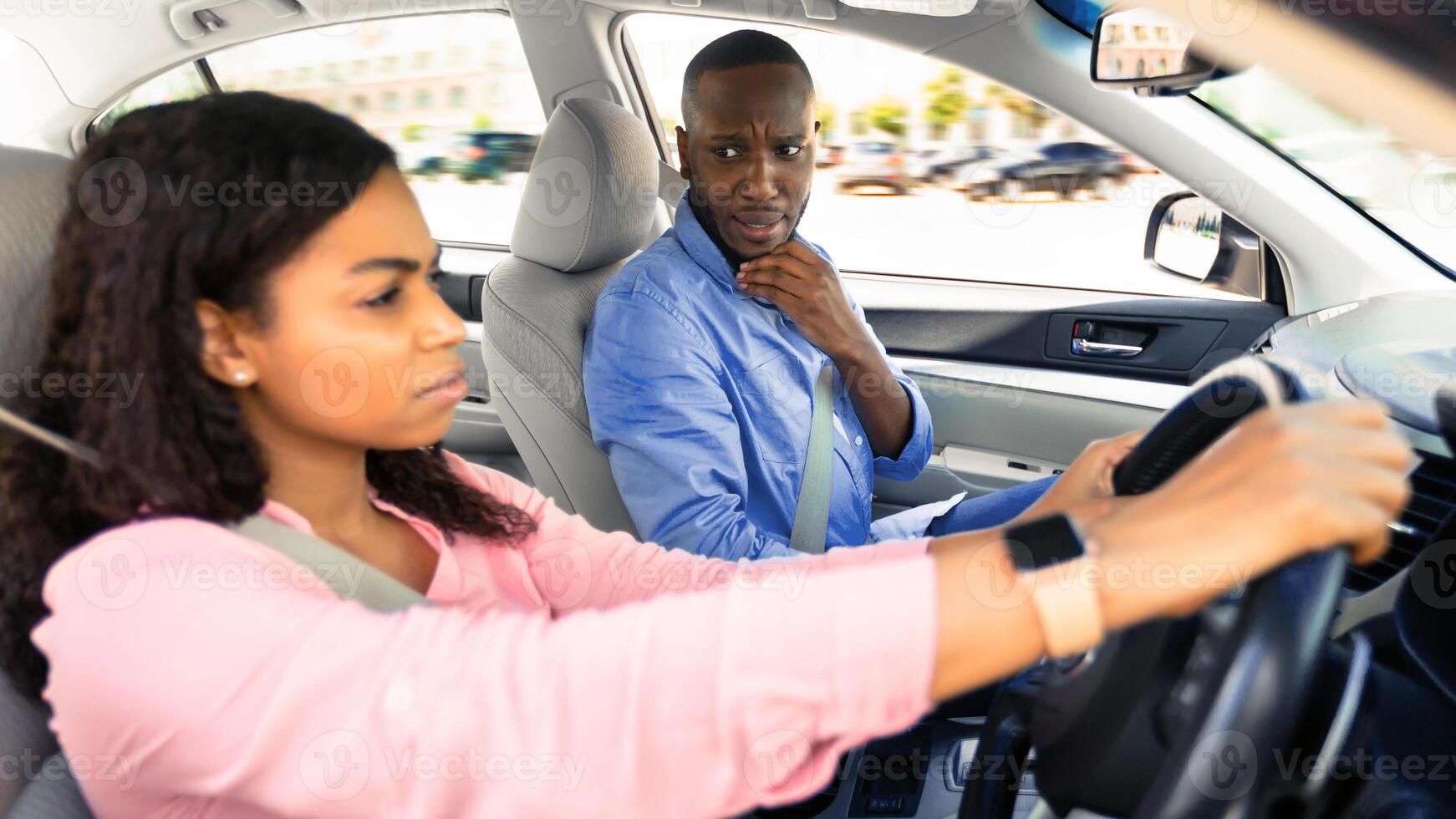 Driving school concept. Scared male course instructor guy looking at serious focused black lady, first time driver sitting inside car watching road, woman having exam for license at training school photo