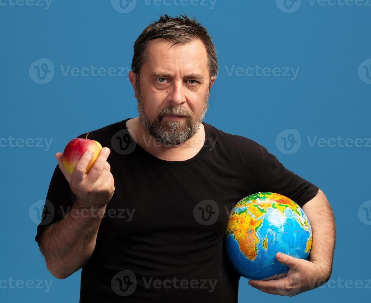 Man holding an apple and a globe, symbolizing knowledge and global awareness through food choices photo