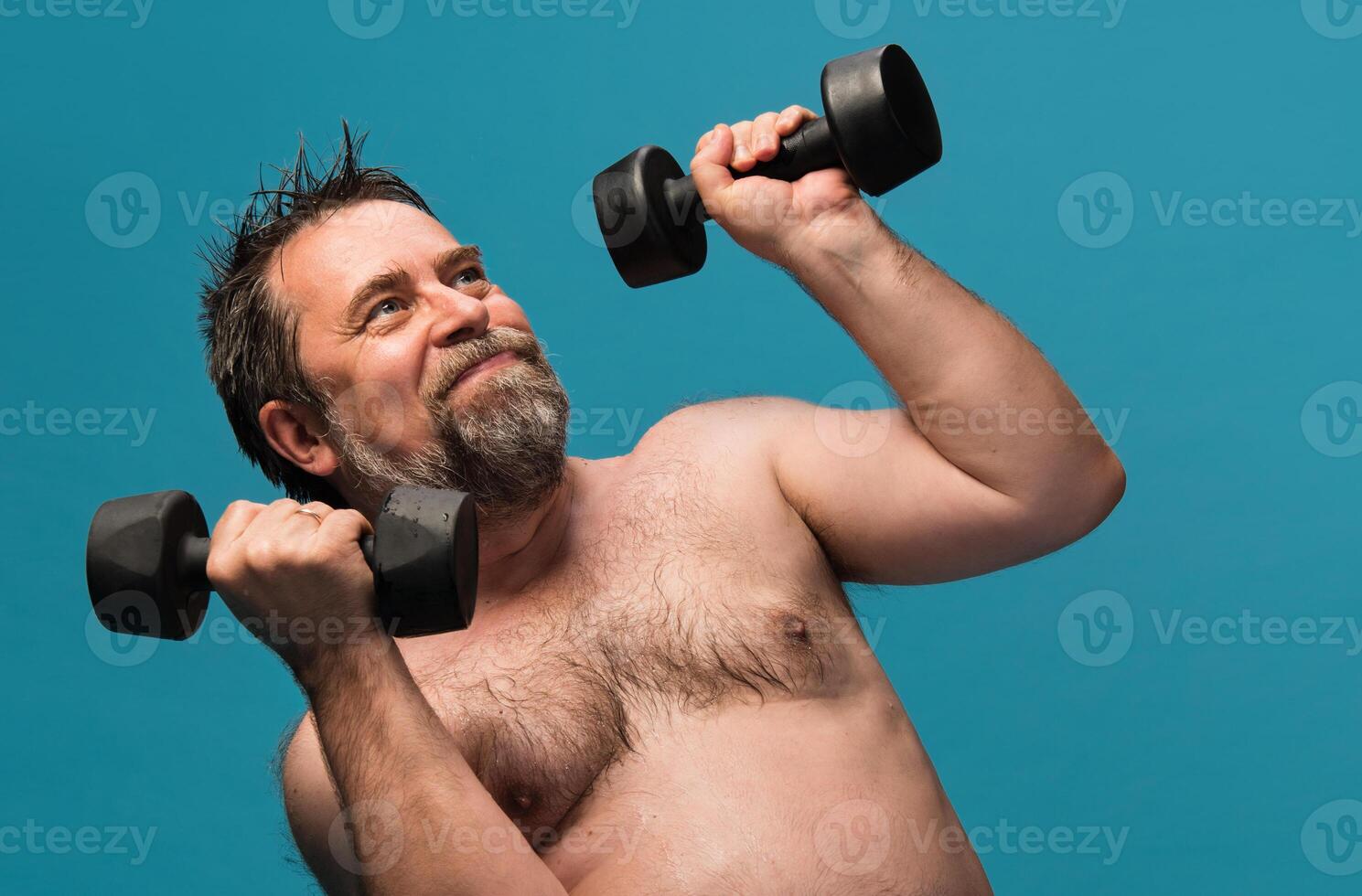 Elderly man lifts dumbbells in a bright fitness studio to improve strength and health photo