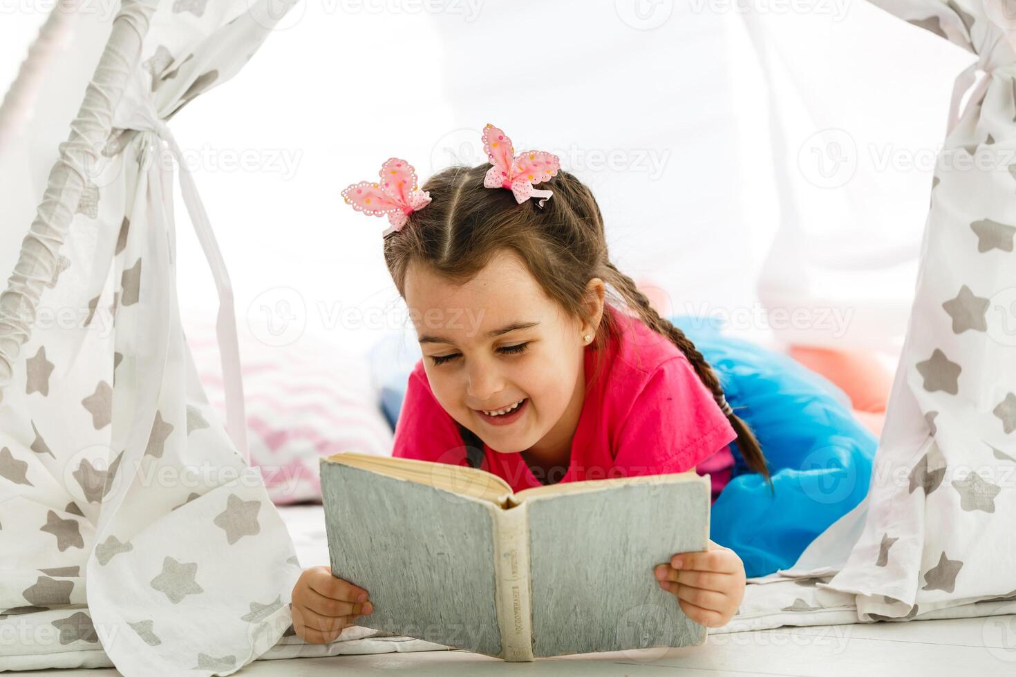 Portrait of pretty little girl reading book in cozy living room at home photo