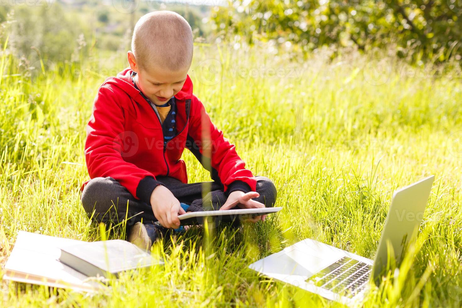 Distance learning. Boy learns autdoor laptop. Doing homework on grass. The child learns in the fresh air. The child's hands and computer photo