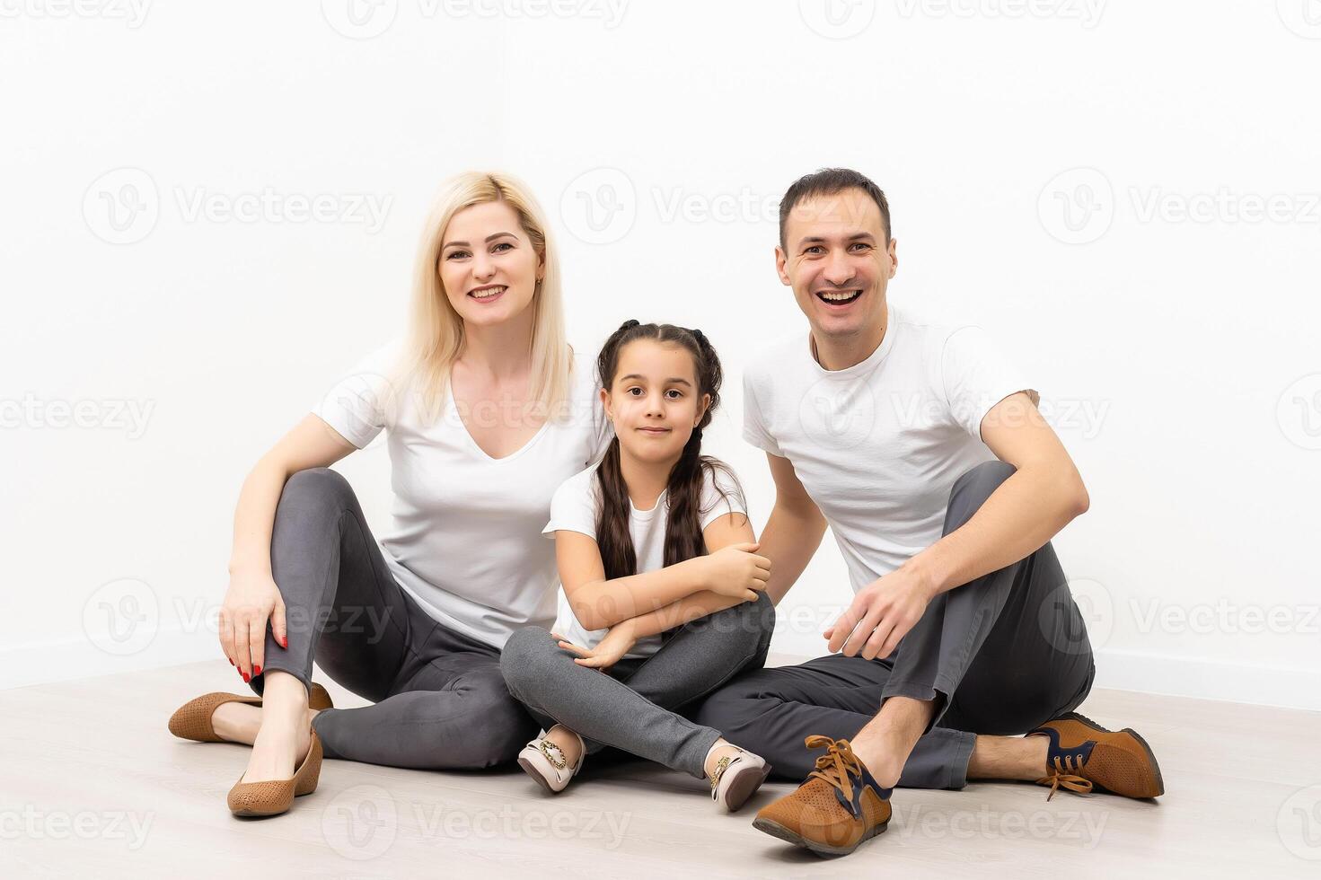 happy family father mother and children sitting on the floor in an empty white wall photo