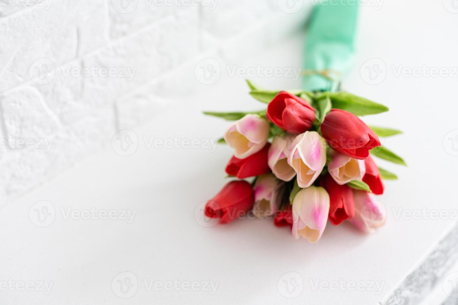 Bouquet of spring tulips with different color flowers wrapped in paper for present on white background photo
