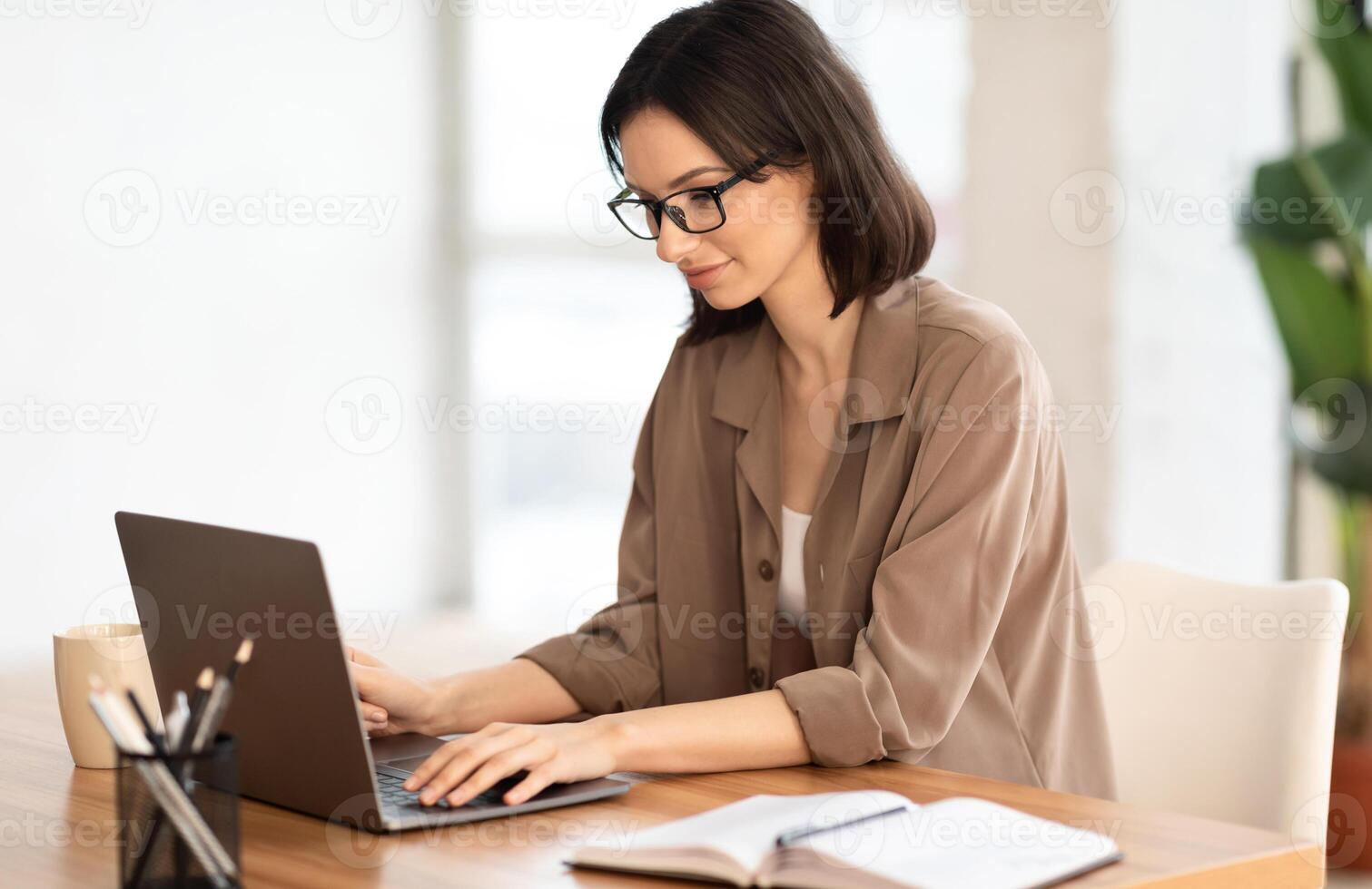 Making New Project. Portrait of satisfied girl in eyeglasses using laptop, working at home, writing blog, free space photo