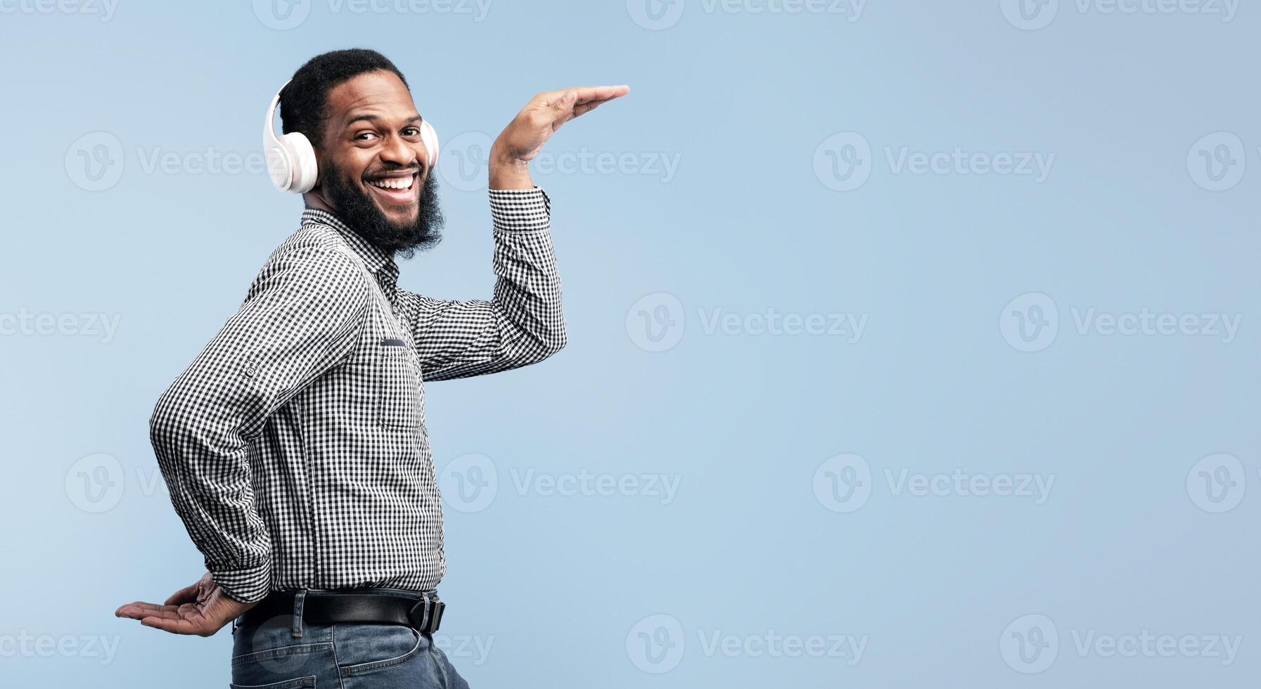 Music Is My Life. Excited african man wearing headset and dancing disco isolated over turquoise studio wall photo