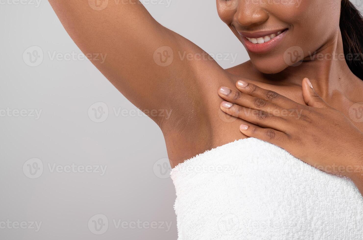 Hair Removal Concept. Unrecognizable Black Female Demonstrating Her Armpit With Smooth Skin, Smiling African American Woman Wrapped In Bath Towel Standing Over Grey Background, Copy Space photo