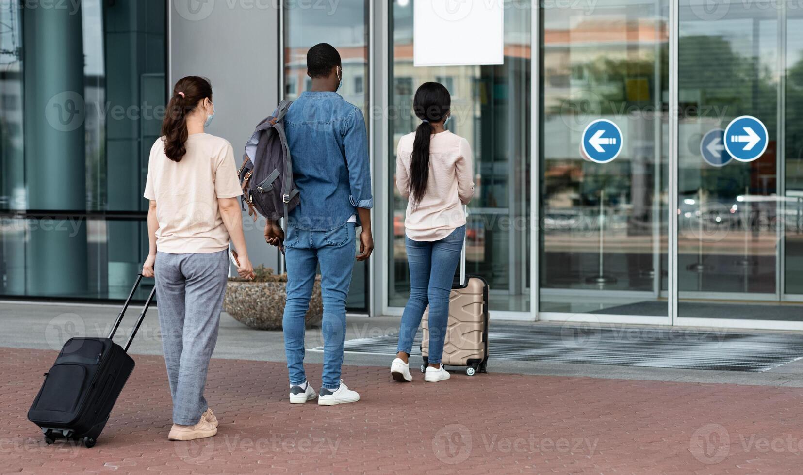 Airport Passengers Standing In Queue To Terminal Entrance With Social Distancing Rules Due To Covid-19 Regulations, Rear View photo