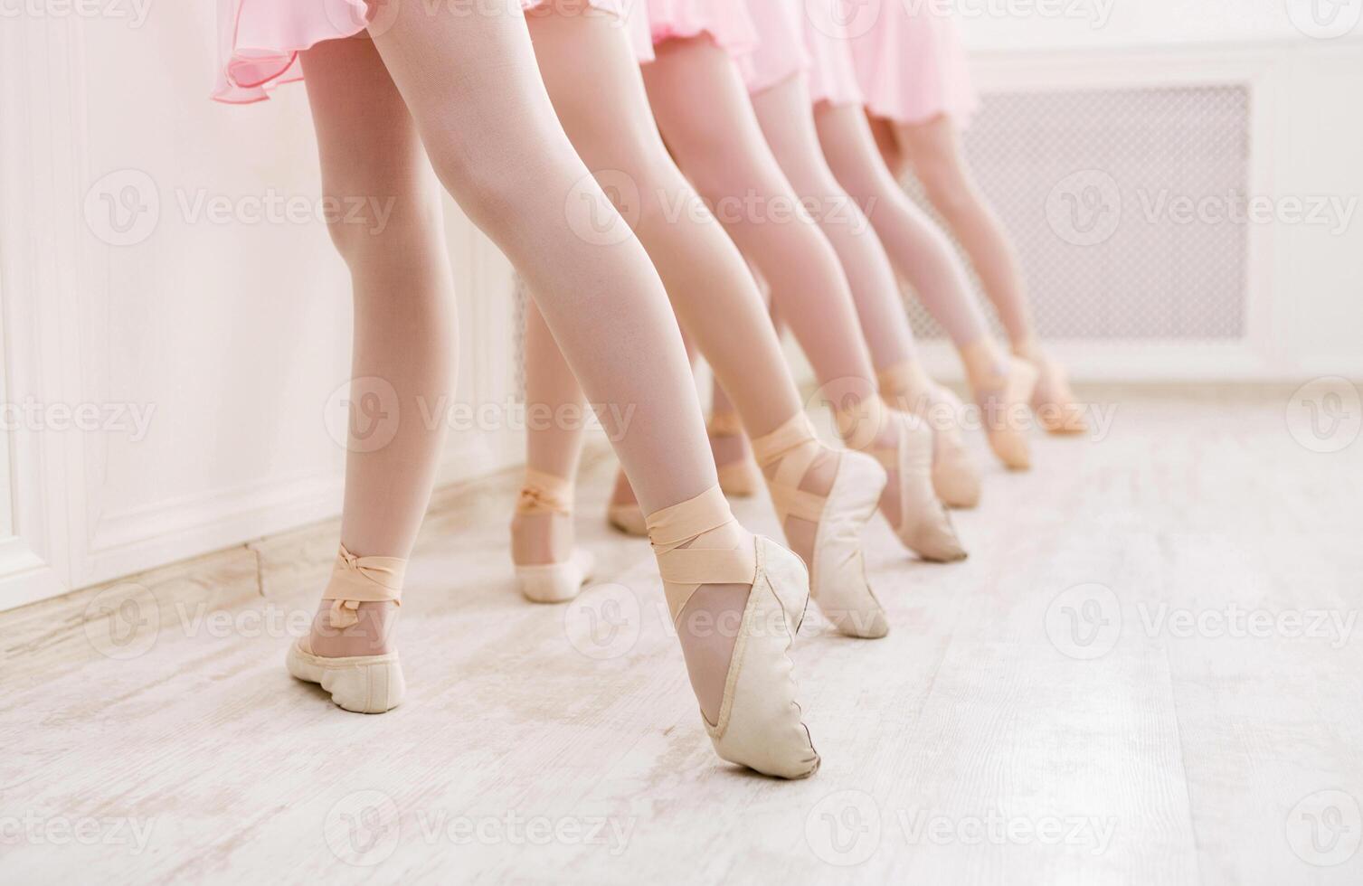 Ballet background, young ballerinas training. Little dancers legs in pointe shoes, making exercises. Classical dance school, copy space photo