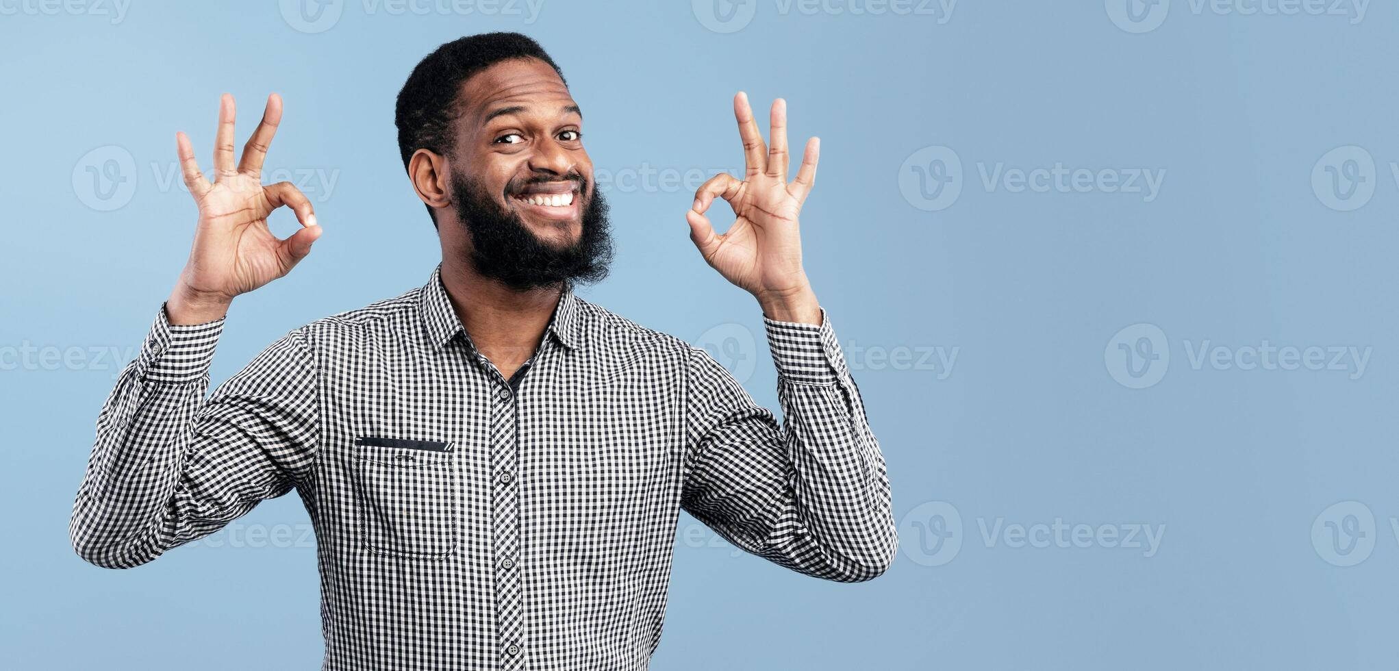 I'm Fine. Close up portrait of happy african business man doing ok gesture isolated over blue studio wall, copyspace photo