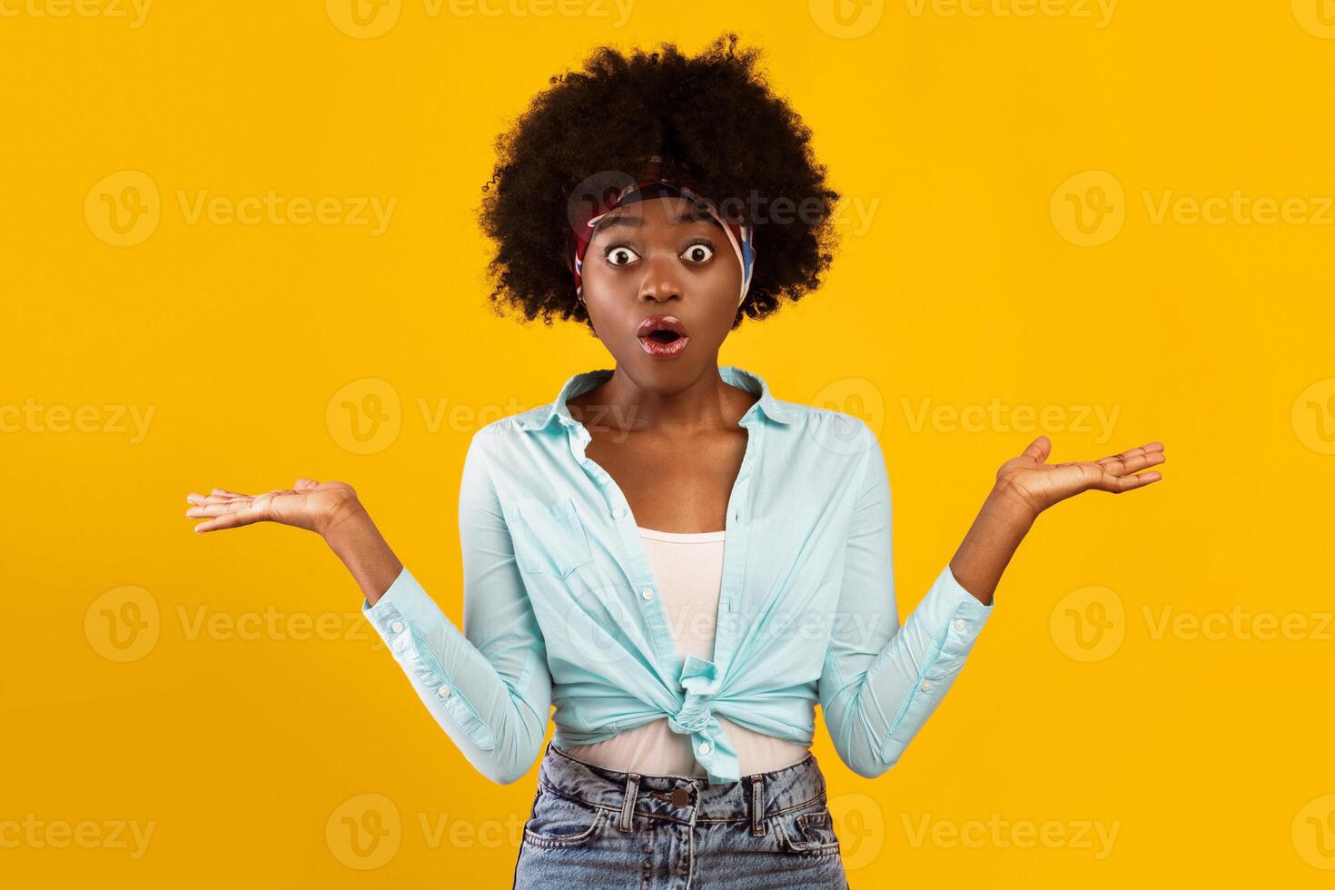 Shocked African American Young Woman Shrugging Shoulders Looking At Camera With Opened Mouth Or Posing Holding Two Invisible Objects On Hands Over Pink Background. Studio Shot photo
