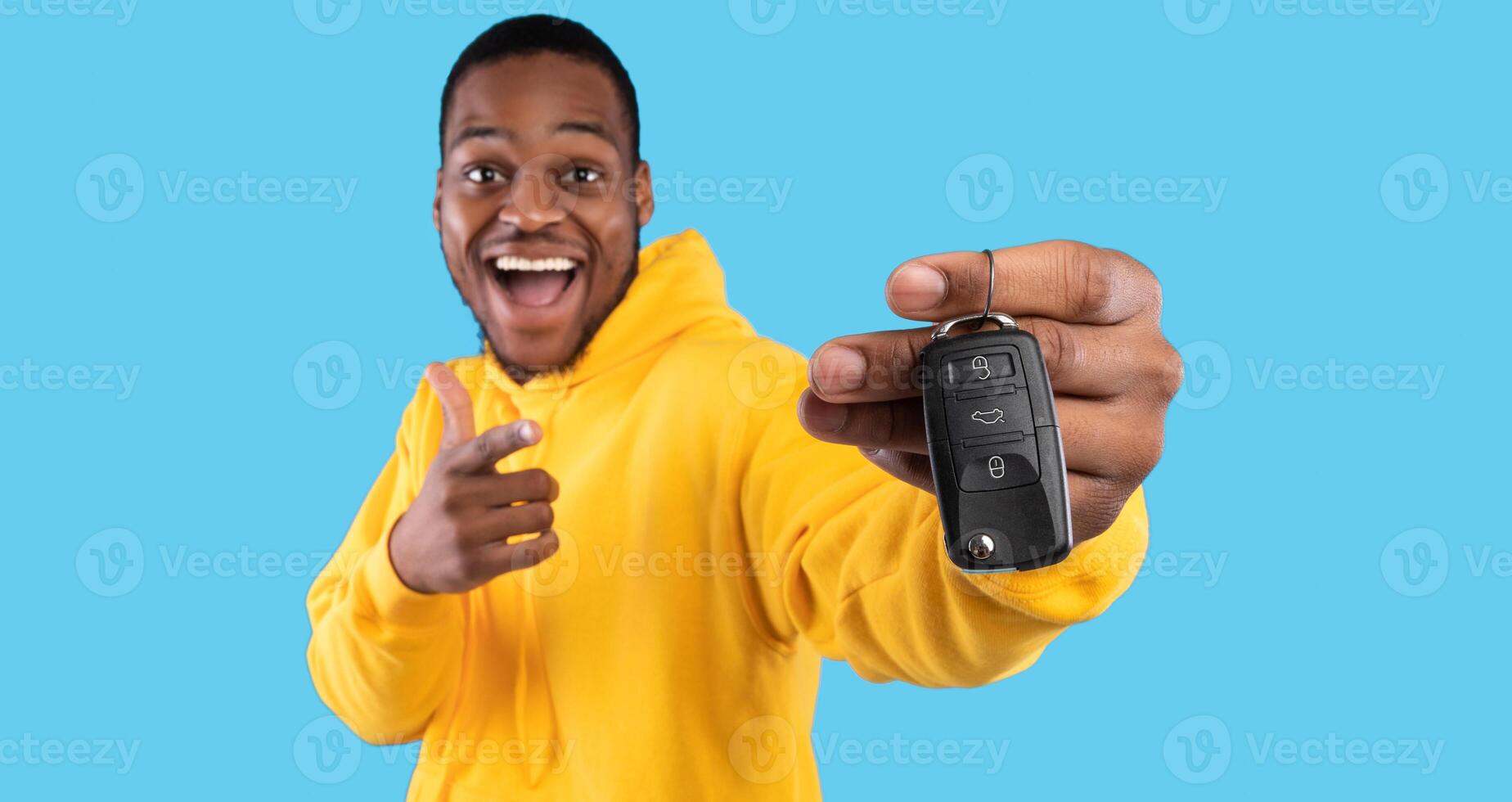 New Car. Excited Black Man Showing Key In Excitement Celebrating Buying New Auto Posing Standing On Blue Studio Background. Dreams Come True, Own Automobile Concept. Panorama, Selective Focus photo