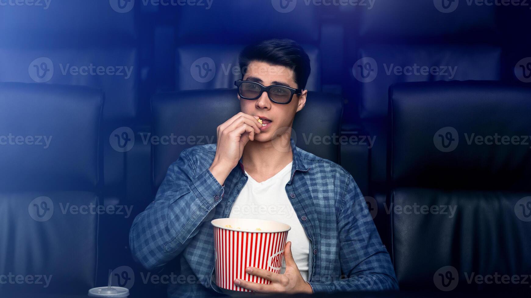 Handsome young man in 3D glasses watching interesting movie in cinema photo