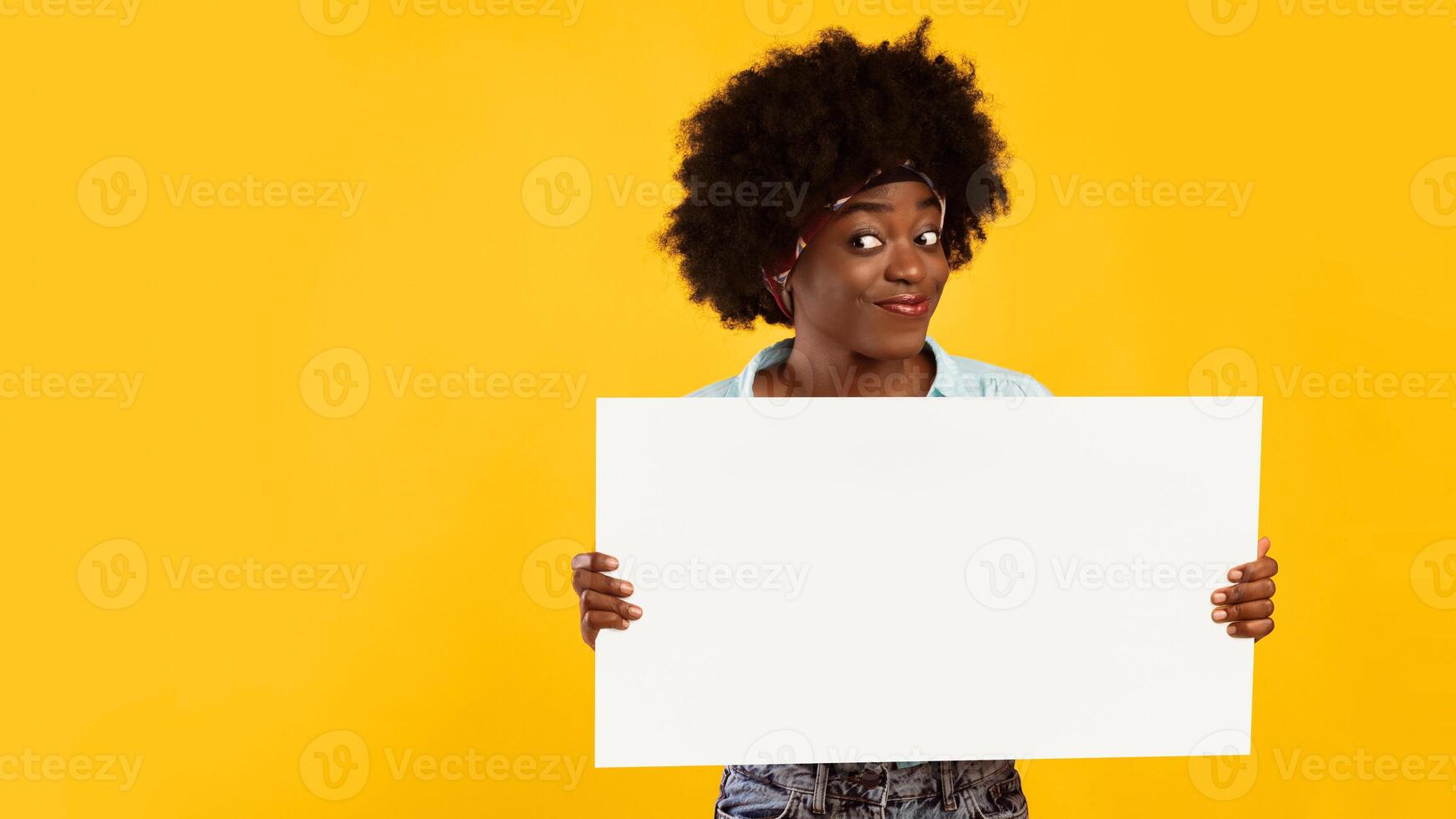 Cheerful Black Young Woman Showing Empty Paper Poster Board For Your Advertisement Posing Standing Over Pink Background. Panorama With Copy Space, Studio Shot, Mockup photo