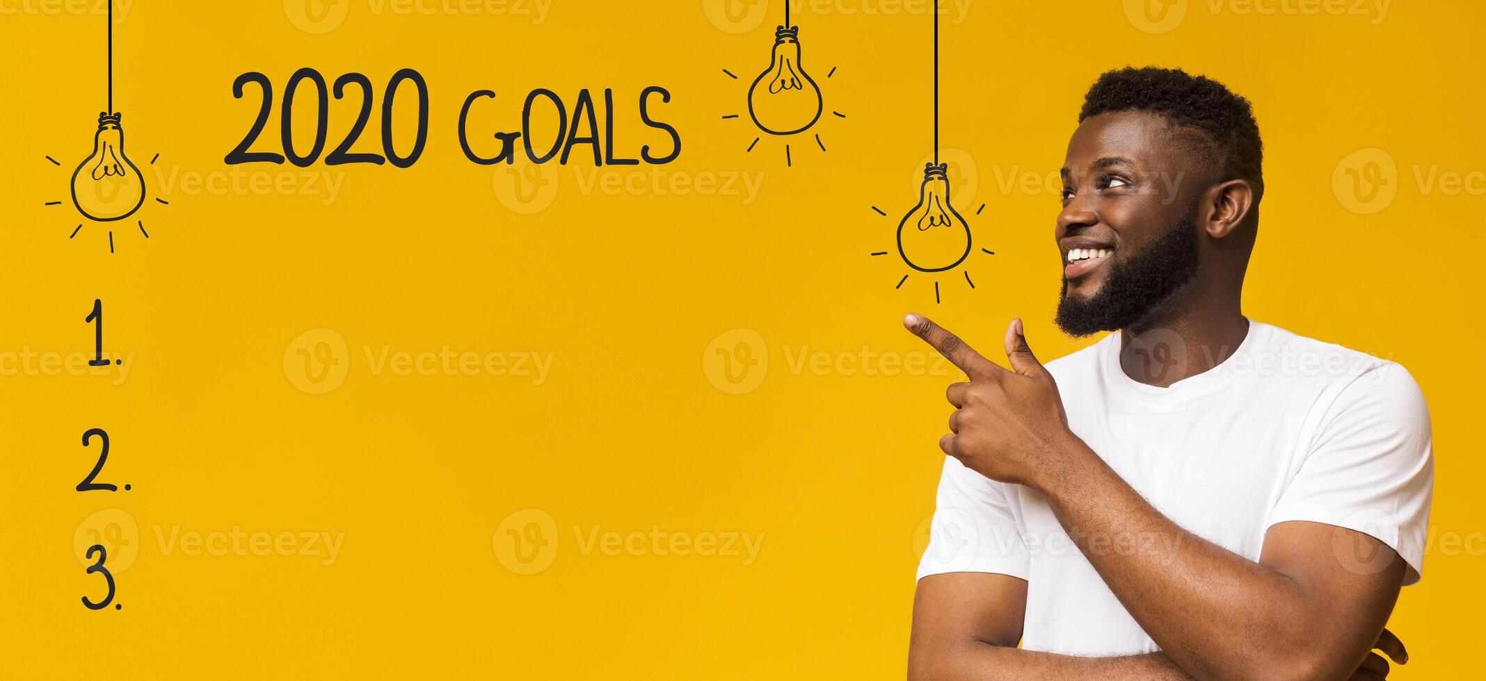 Future plans. Cheerful black man pointing at checklist with 2020 goals, yellow background photo