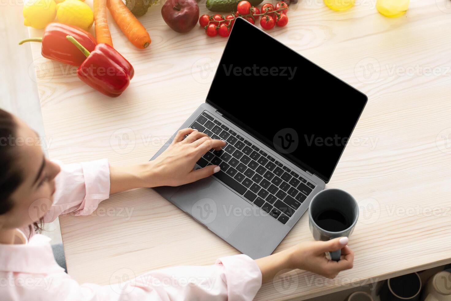 Breakfast Concept. Above top high angle view of young female using personal computer with black empty screen for mock up design, checking email or browsing internet sitting at table drinking coffee photo