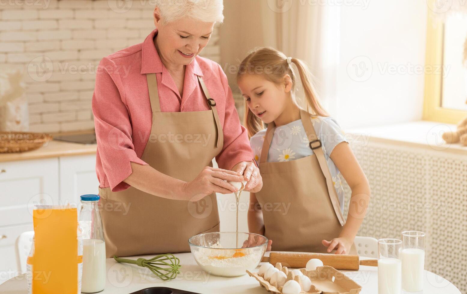 Baking together. Older lady and little girl making dough together in kitchen photo