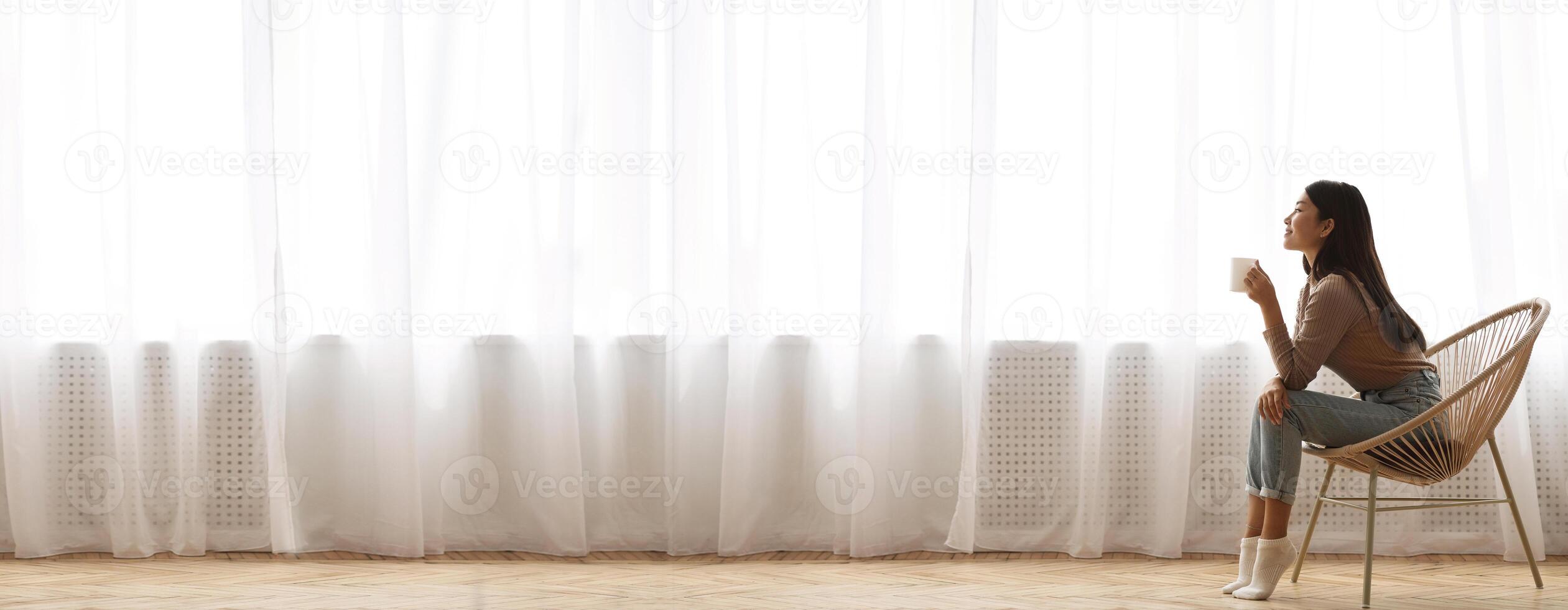 Morning Relax. Wide Shot Of Asian Girl Sitting In Wicker Chair And Drinking Coffee In Front Of Window, Extreme Long Banner, Panorama With Free Space photo