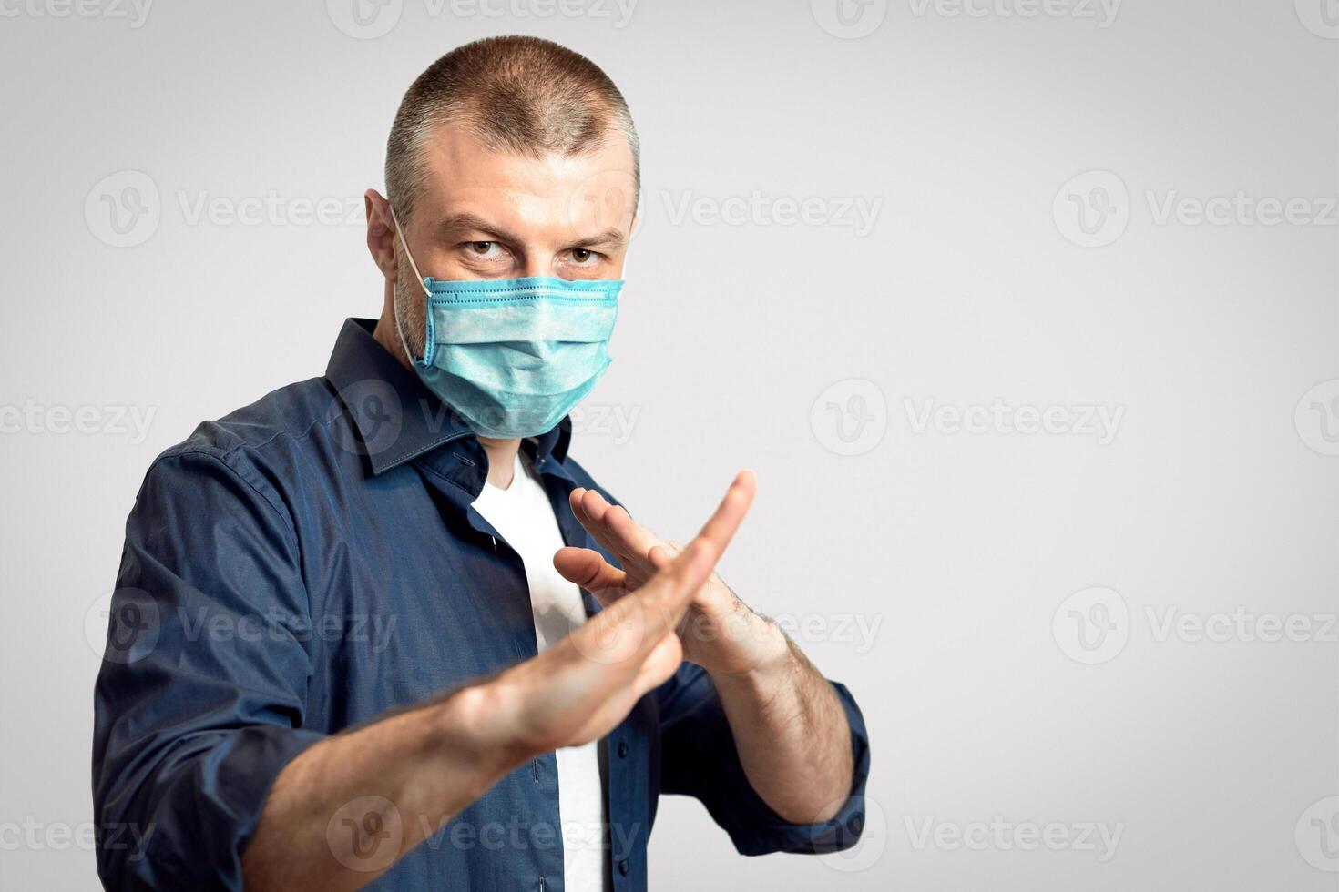 Coronavirus Protection. Man In Protective Medical Mask Standing In Ready To Fight Pose Over Gray Studio Background. Panorama, Selective Focus photo