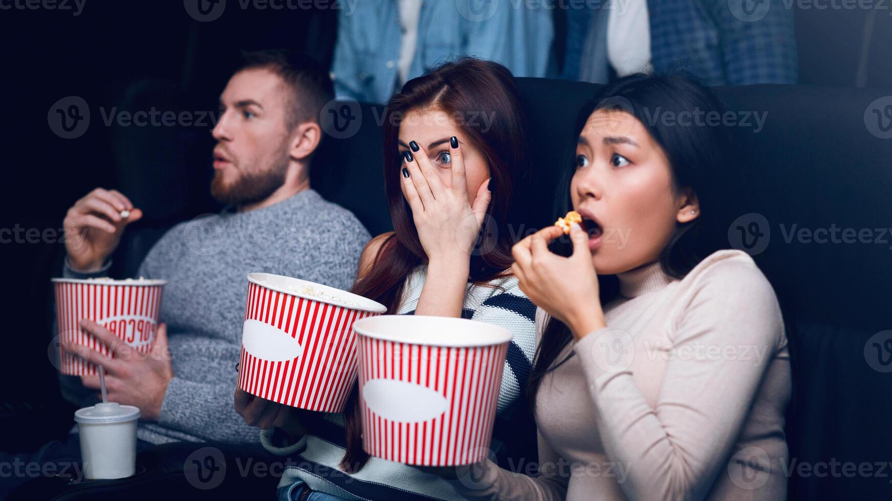 Leisure activity concept. Young people scared of horror movie in film theater photo