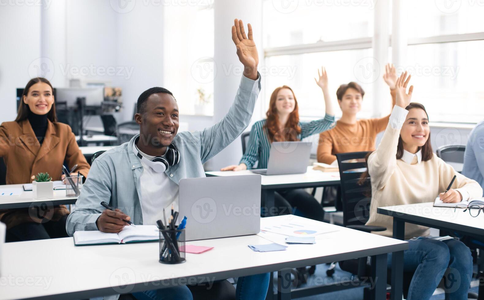 Presentation, Convention Concept. Portrait of smiling international people participating in seminar at modern office, raising hands up to ask question or to volunteer, diverse group sitting at tables photo