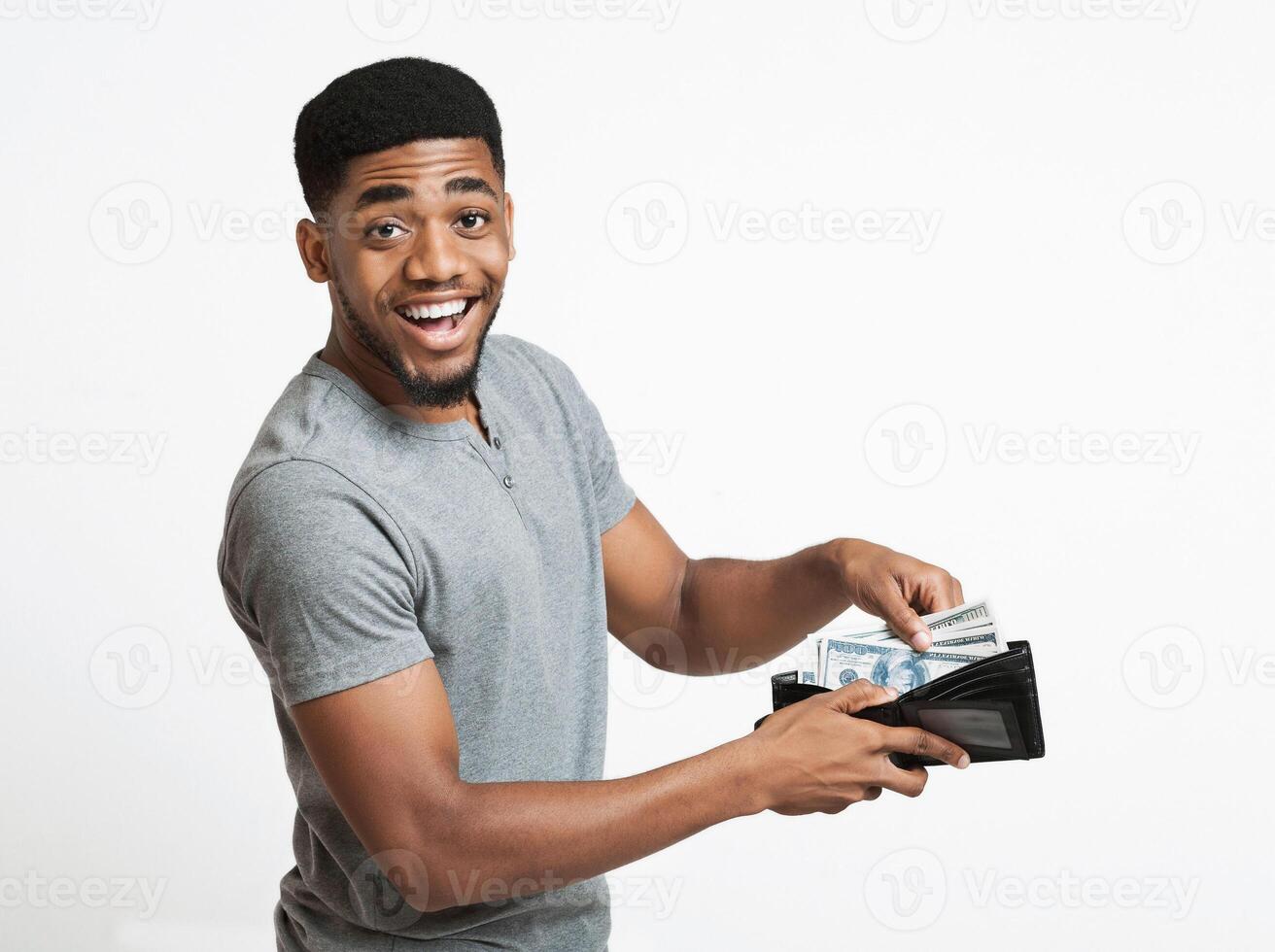 Finance, investment and money saving. Excited african-american man putting banknotes into wallet, white studio background photo