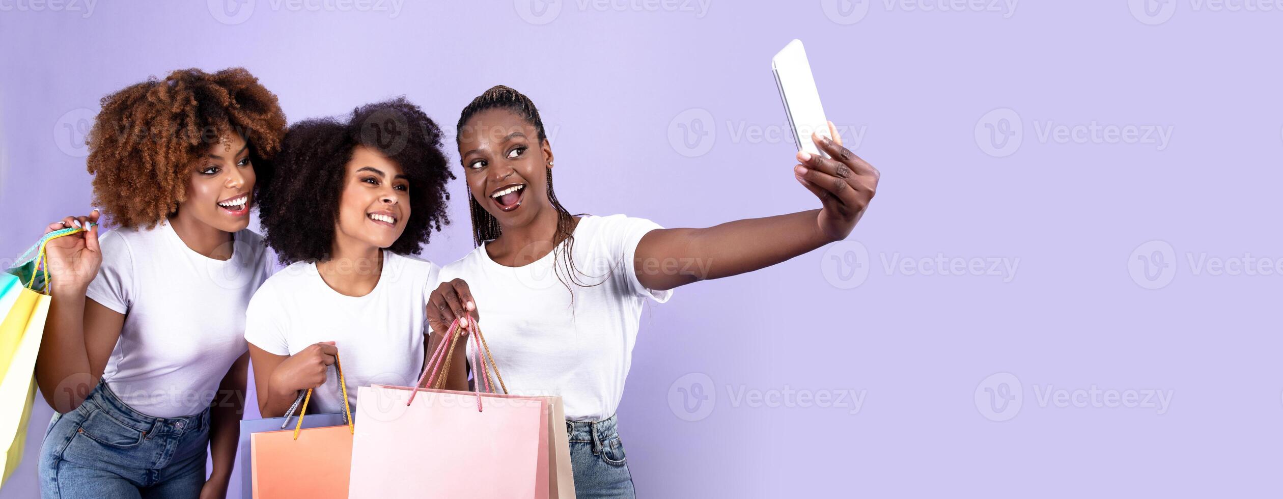 Excited Black Girlfriends Trio Making Selfie On Smartphone While Shopping And Having Fun, Posing With Paper Shopper Bags Together On Purple Studio Background, Smiling To Phone photo