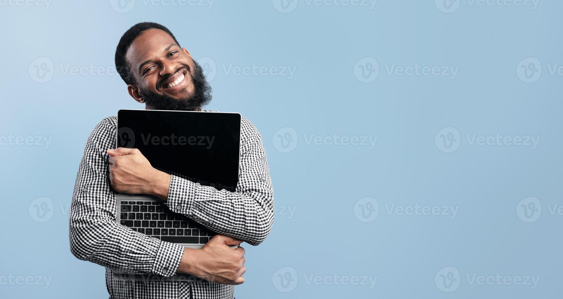 Funny crazy african guy embracing personal computer with empty display, isolated over turquoise studio background photo