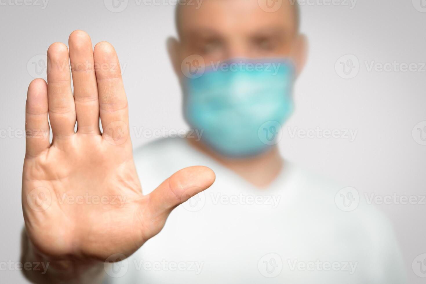 Stop Coronavirus. Unrecognizable Man In Medical Mask Gesturing Stop Standing Over Gray Background In Studio. Panorama, Selective Focus photo