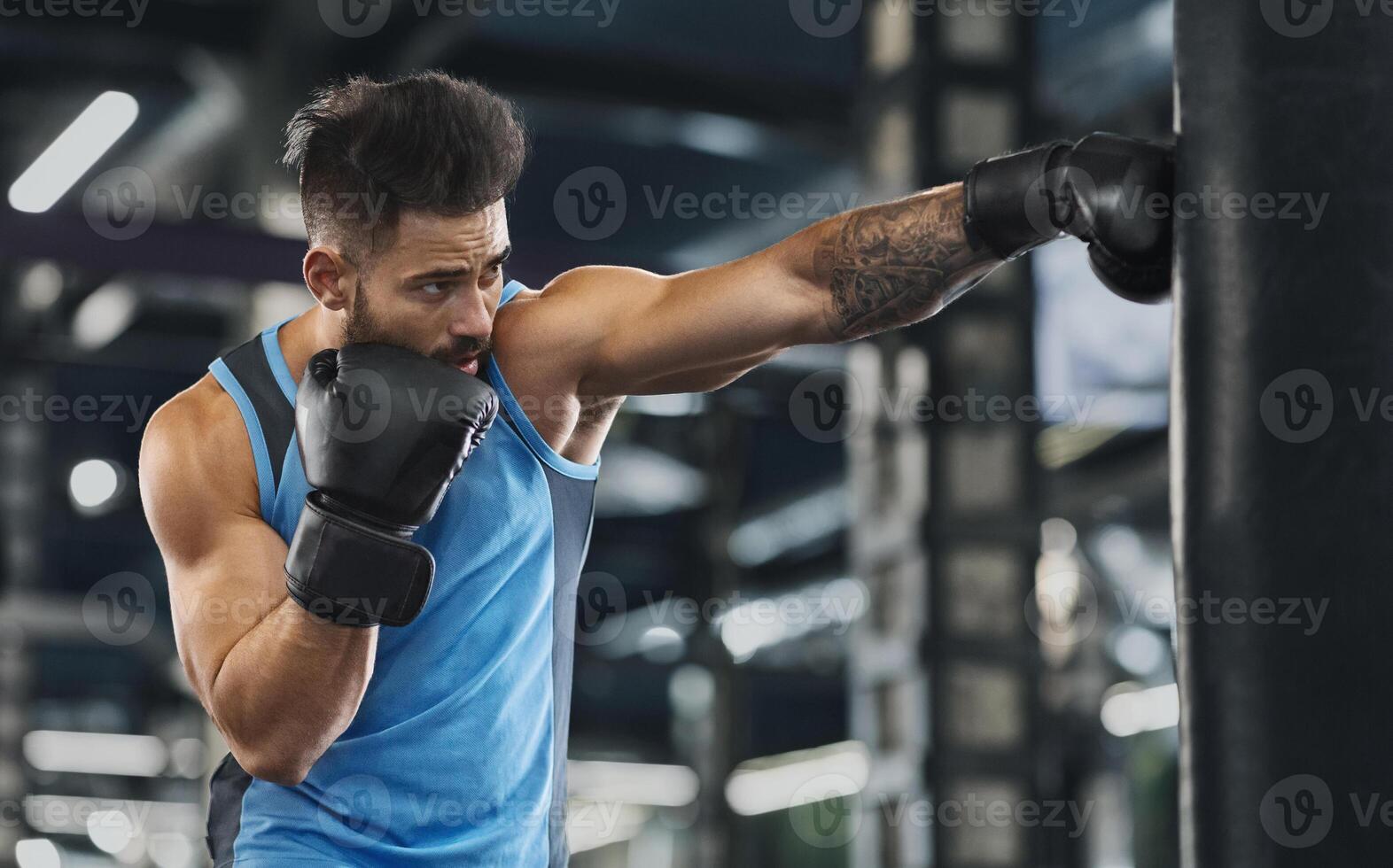 Young sportsman boxing workout at gym, guy punching boxing bag, free space photo