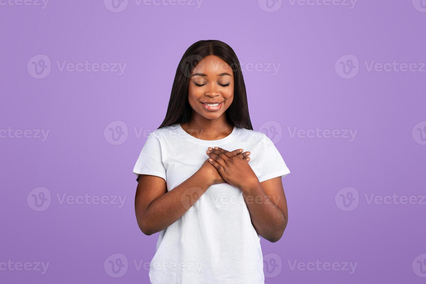 Thank You. Portrait Of Grateful Young Black Couple Holding And Pressing Hands To Chest Expressing Gratitude Posing Over Blue Studio Background With Closed Eyes. Appreciation Concept photo