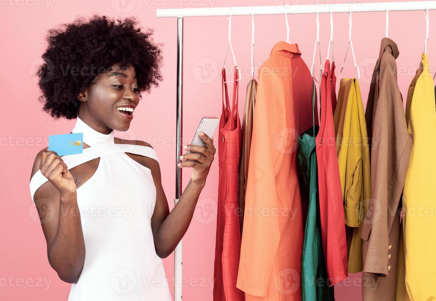 Joyful Black Shopaholic Woman Using Smartphone With Mobile Shopping Application Buying Clothes Online Standing Over Pink Background In Studio. Female Customer Purchasing Outfits Via Phone photo