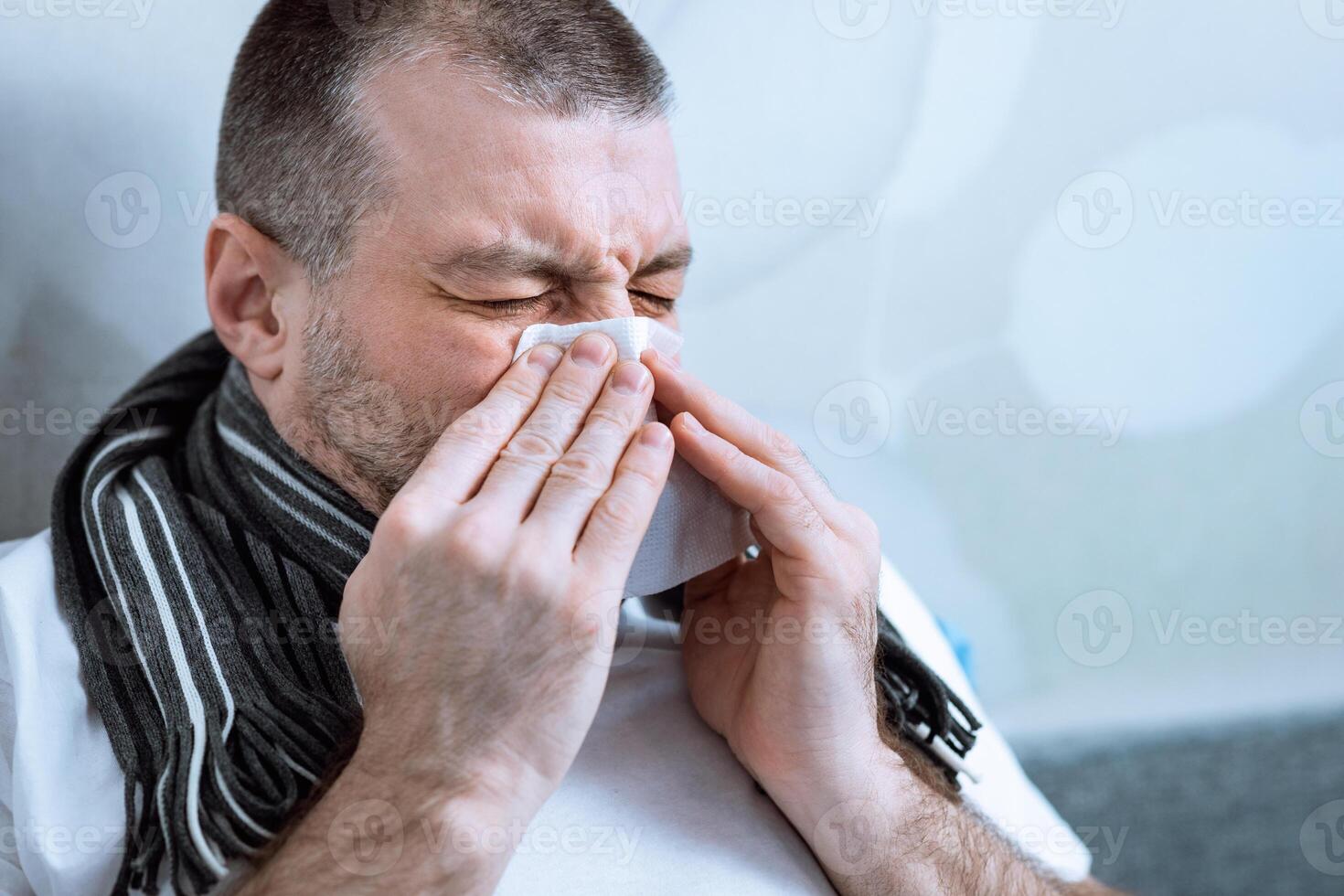 Sick Man Blowing Nose In Paper Tissue Having Fever Lying In Bed At Home During Coronavirus Epidemic Outbreak. Selective Focus photo
