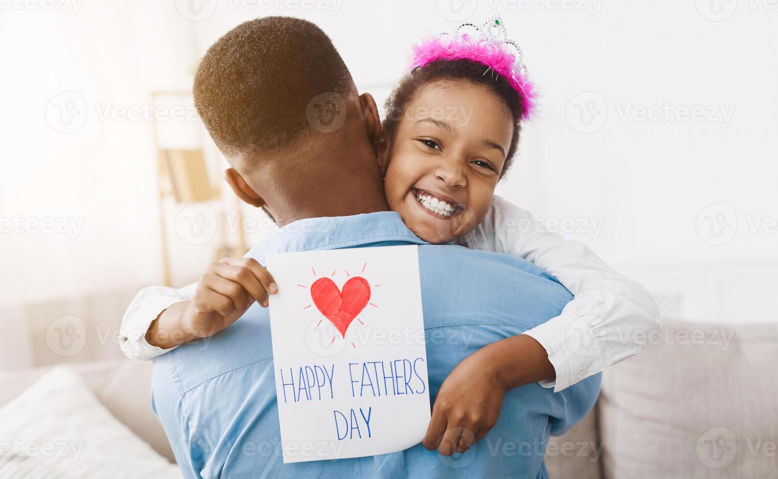 Little girl hugging dad and giving him postcard, congratulating with father's day photo