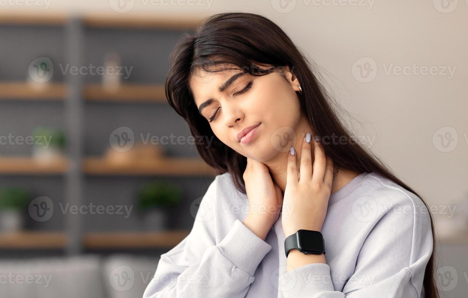 Exhausted Person Concept. Tired young woman sitting at desk massaging sore neck, feeling pain after hard working long hours, free copy space. Female suffering from inflammation, student taking break photo