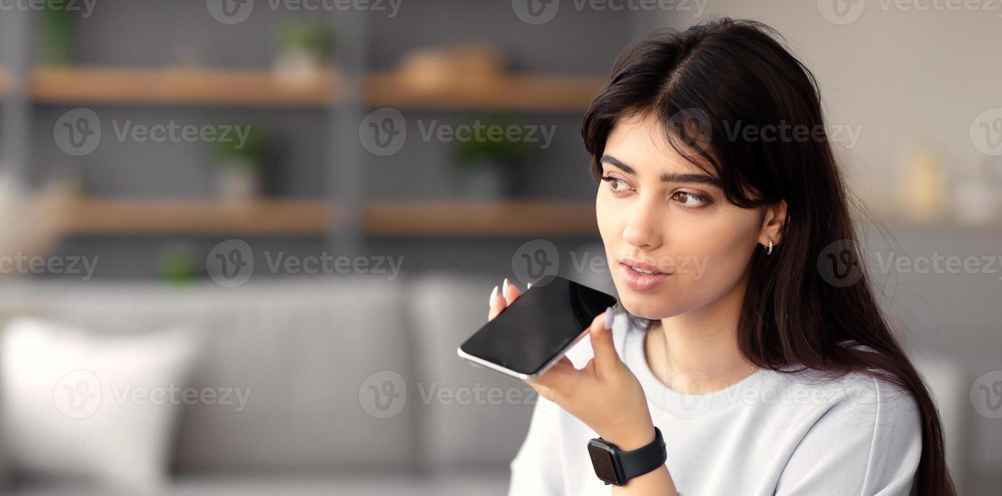 Work From Home. Portrait Of Young Business Lady Using Voice Search Assistant, Talking On Mobile Phone And Using Laptop Computer. Woman Sitting At Desk With Pc At Home Office, Free Copy Space photo