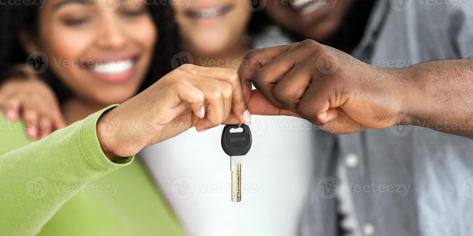 Housing concept. Happy african american family of three holding keys from their new flat, selective focus on hands, closeup. photo