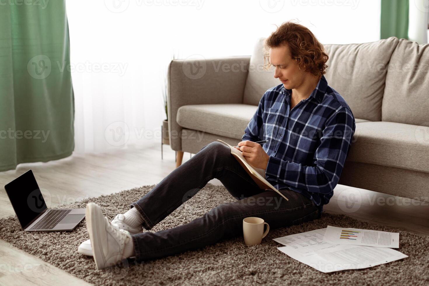 Millennial Guy Learning Taking Notes Sitting On Floor At Home. Adult Learner Student Preparing For University Exam In Living Room. Distant Education, E-Learning Concept photo
