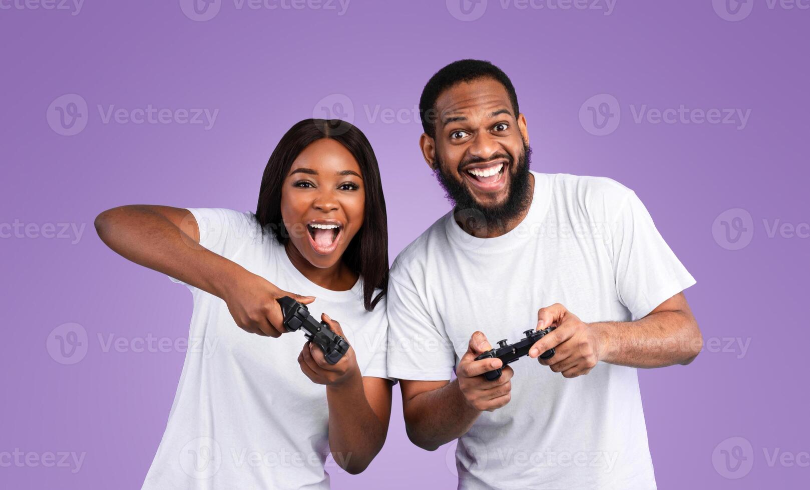 Having Fun. Portrait of excited African American couple playing games together with a black controller, holding and using joysticks over blue studio background, banner. Free Time Entertainment photo