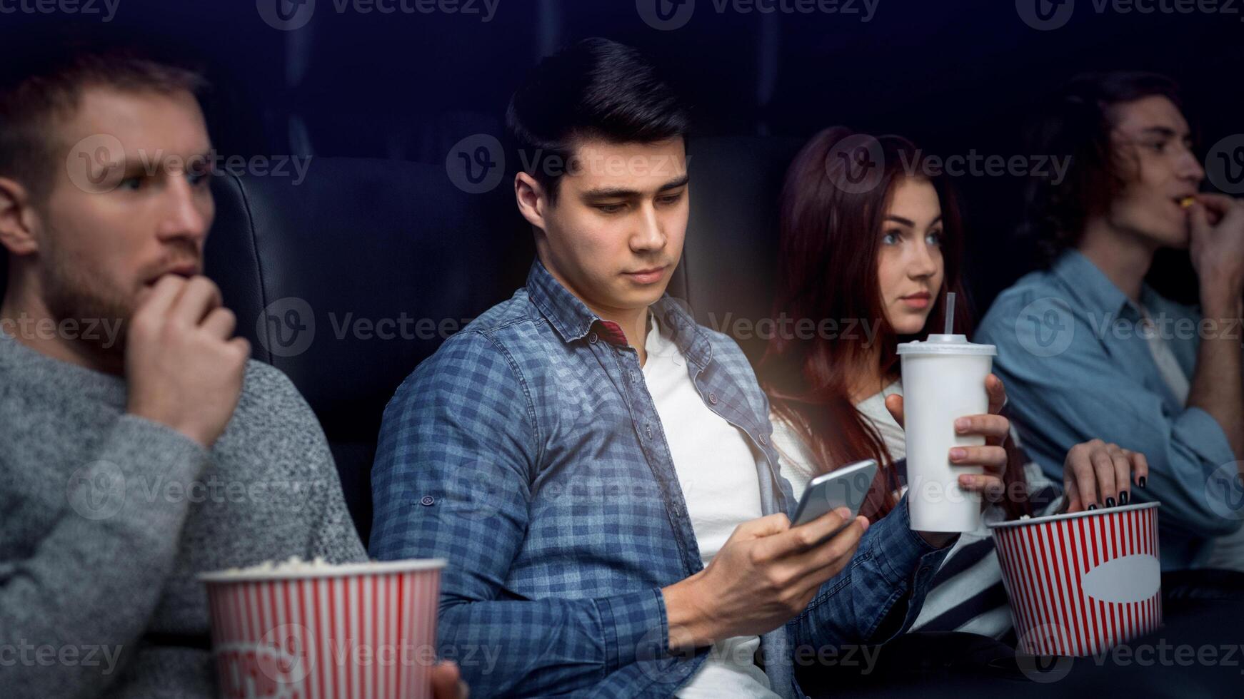 On movie night. Young man using mobile phone while watching film in cinema photo