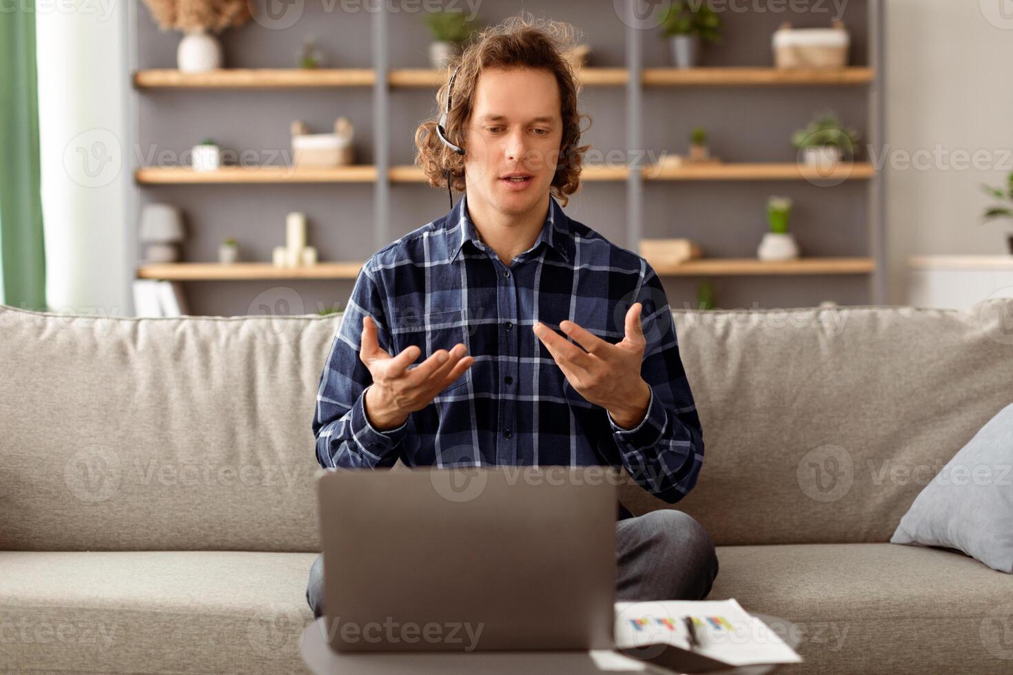 Virtual Meeting. Freelancer Man Having Call At Laptop Talking To Computer Webcam Wearing Headset Sitting On Sofa At Home. Distance Work, Online Communication Concept. Selective Focus photo