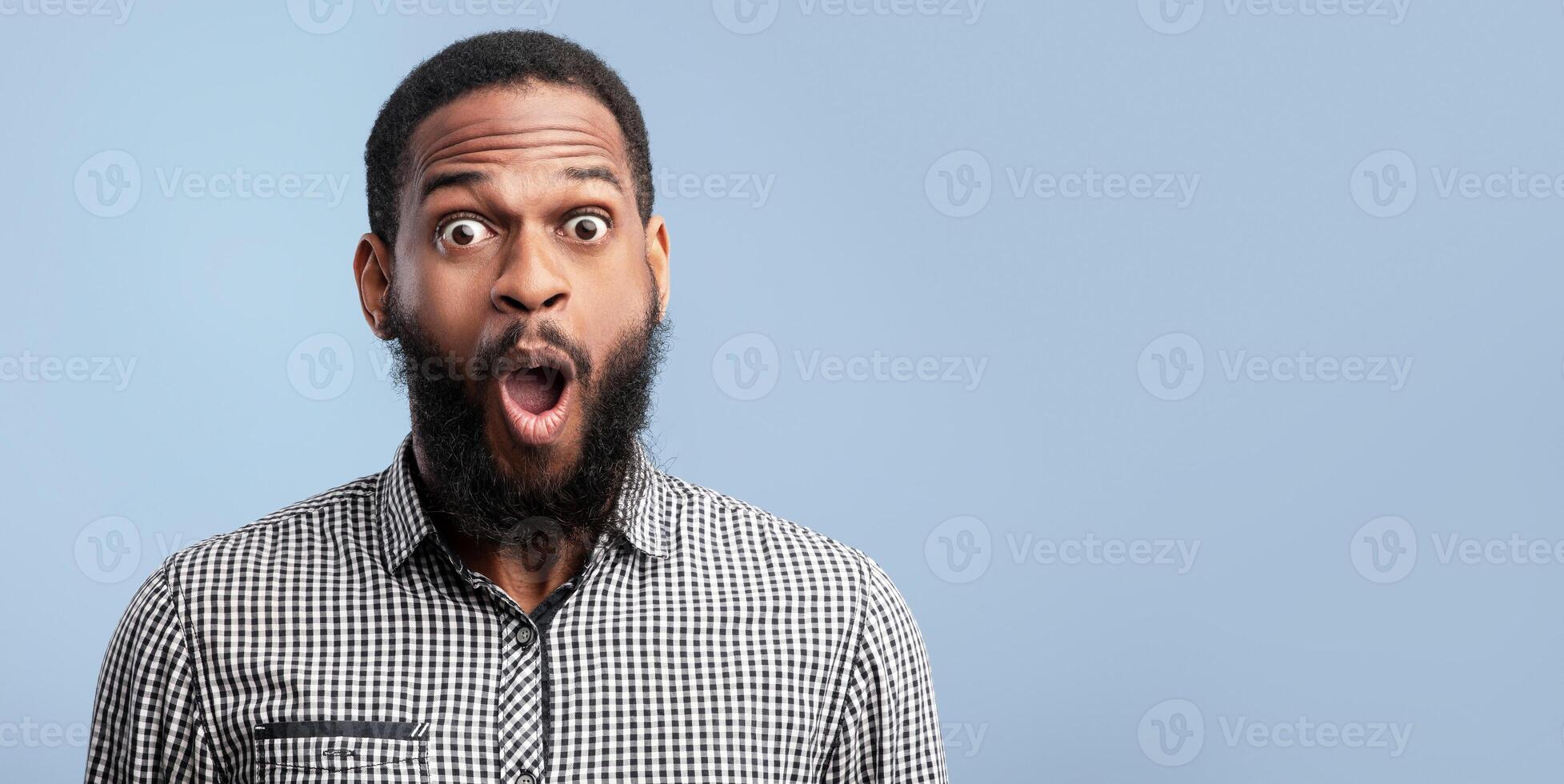 Wow. Closeup headshot of surprised african american guy looking at camera isolated over blue studio wall photo
