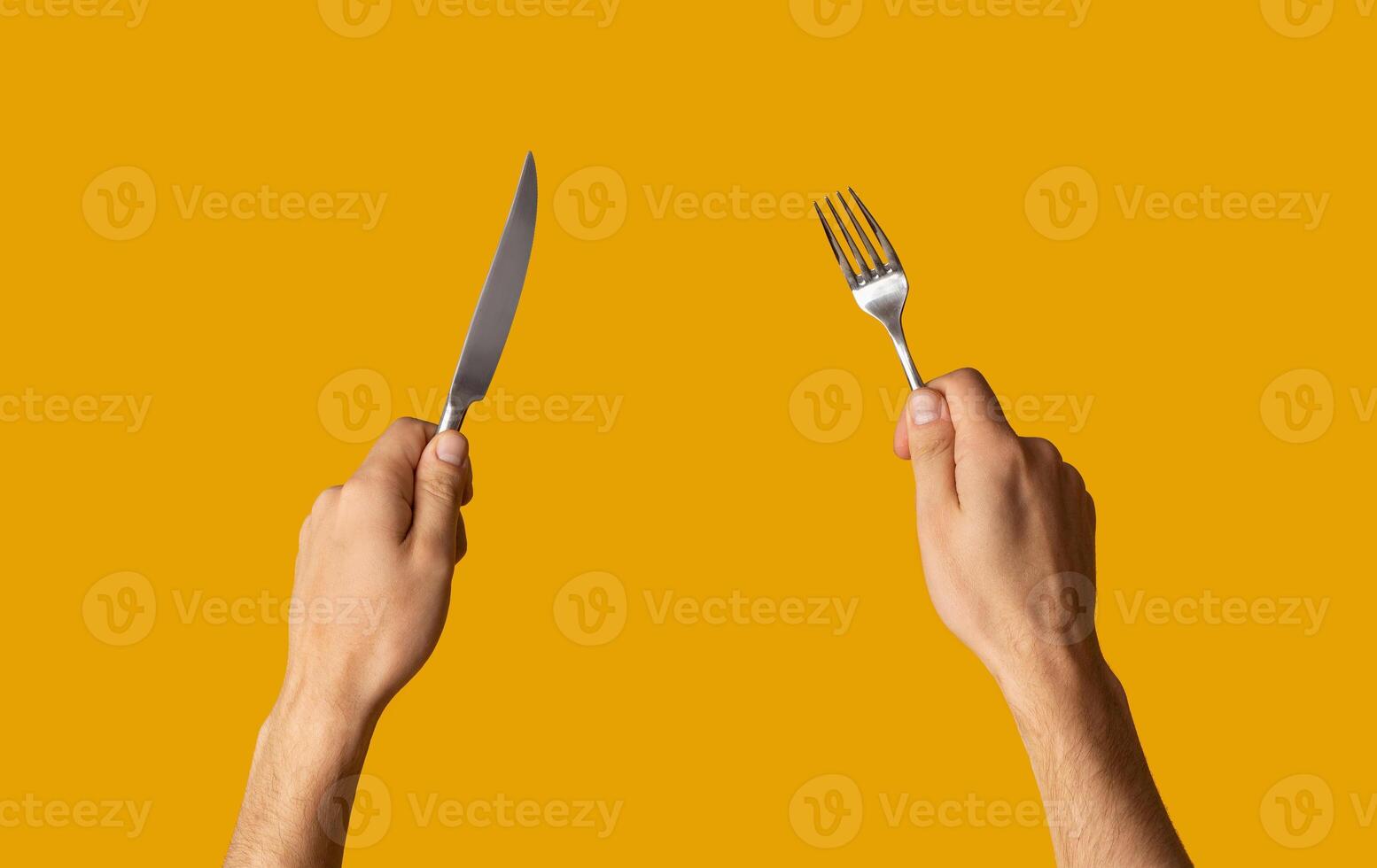 Close up of young guy holding knife and fork on orange background, panorama photo