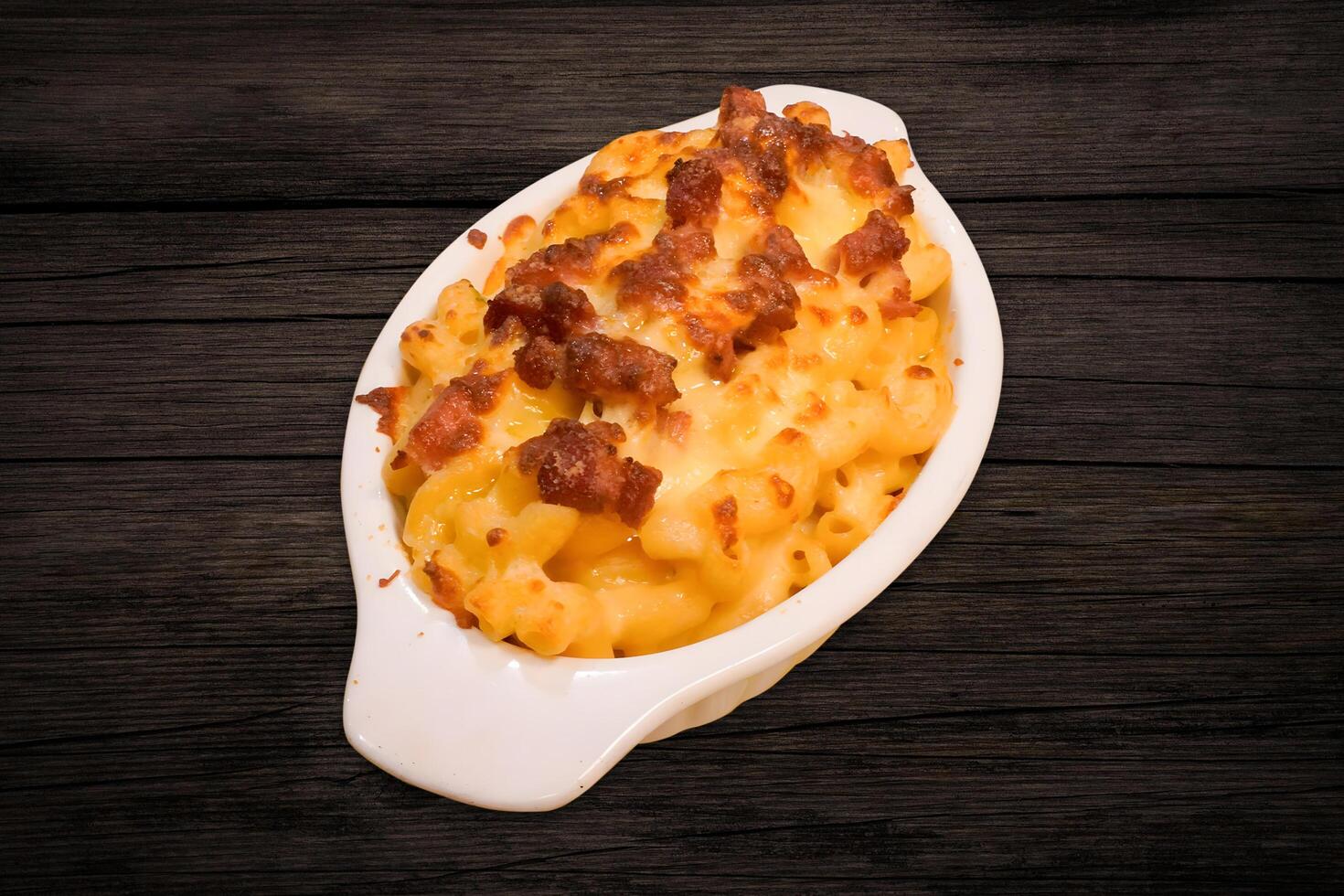 Macaroni filled with meat and mozzarella cheese in a white bowl on a wooden table photo