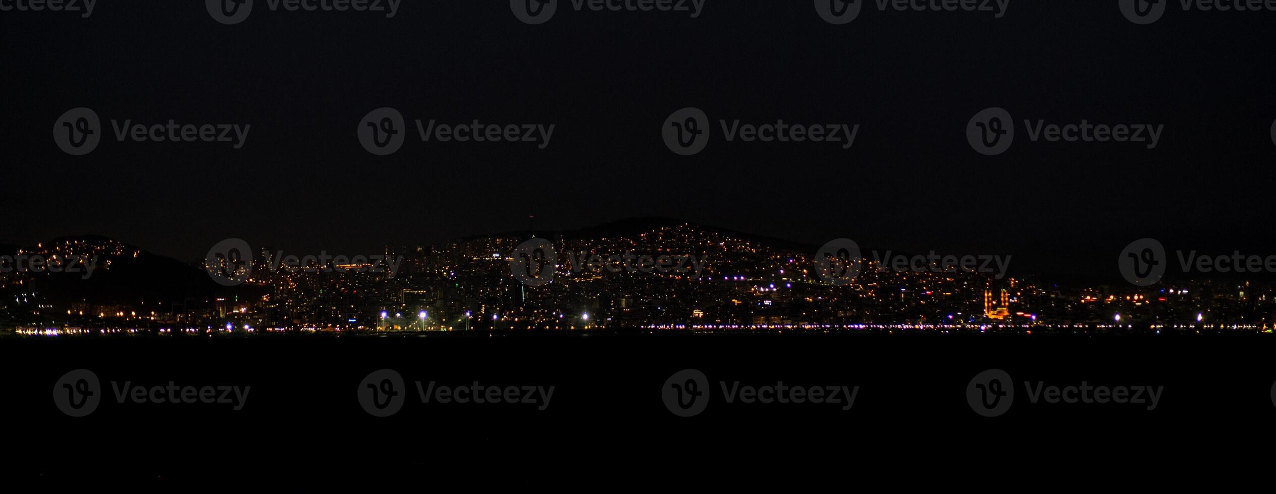 The skyline of Istanbul glows at night, showcasing bright lights over the water photo