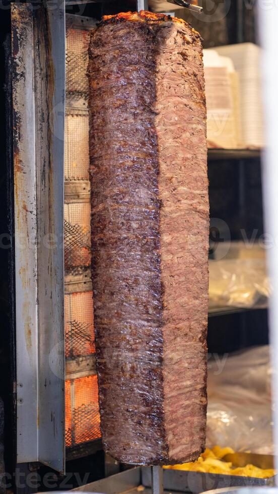 Chef skillfully cutting shawarma meat from a rotating skewer. Freshly cooked photo