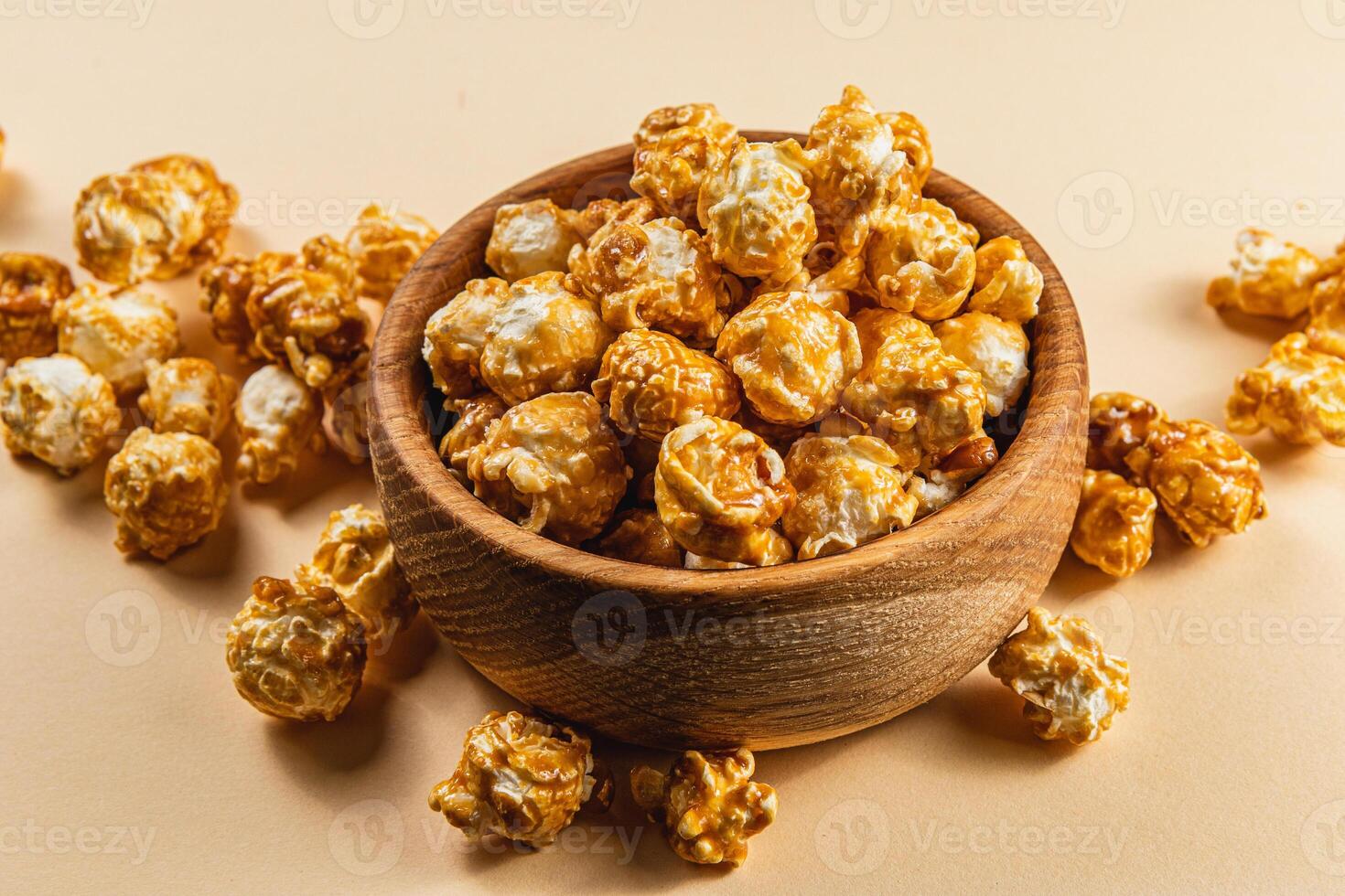Caramelized popcorn in a wooden bowl on a light background photo